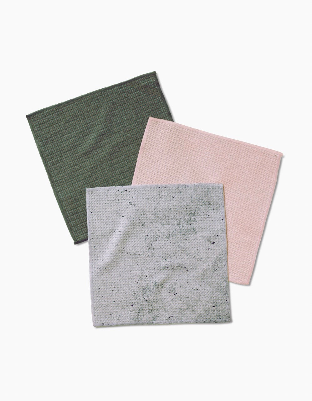 Three square dishcloths from Kailee Wright’s The Wright Set are laid flat on a white background. Green, pink, and light gray with dark speckles, they feature Geoweave fabric for textured, waffle-like enhanced cleaning.
