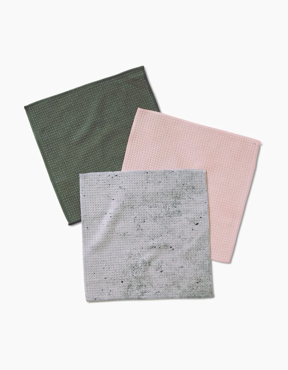 Three square dishcloths from Kailee Wright’s The Wright Set are laid flat on a white background. Green, pink, and light gray with dark speckles, they feature Geoweave fabric for textured, waffle-like enhanced cleaning.