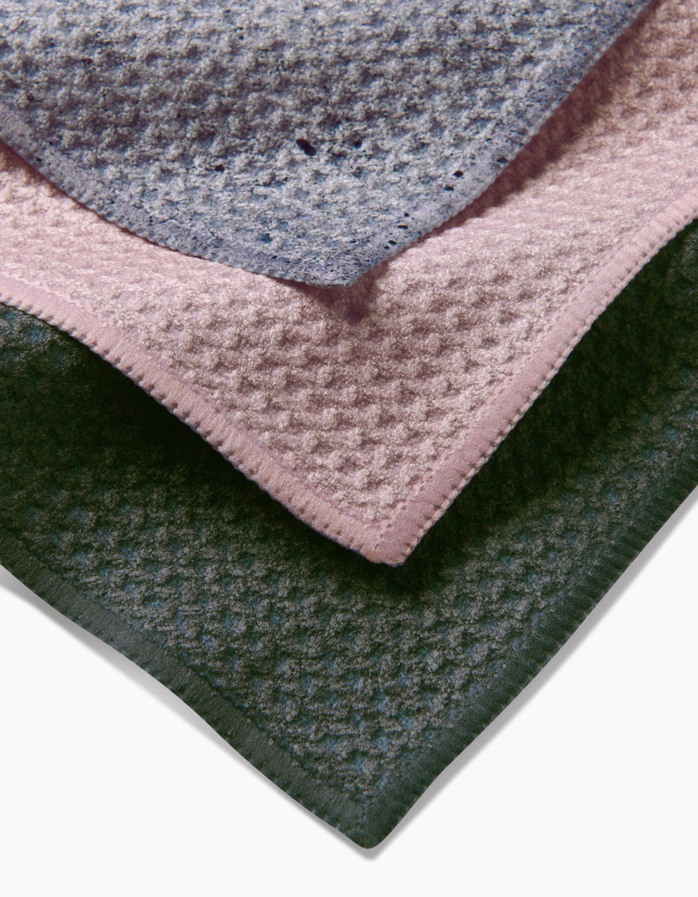 The Wright Set by Kailee Wright features three waffle-patterned dishcloths—grey, pink, and dark green—crafted from recycled materials and shown layered on a white background.