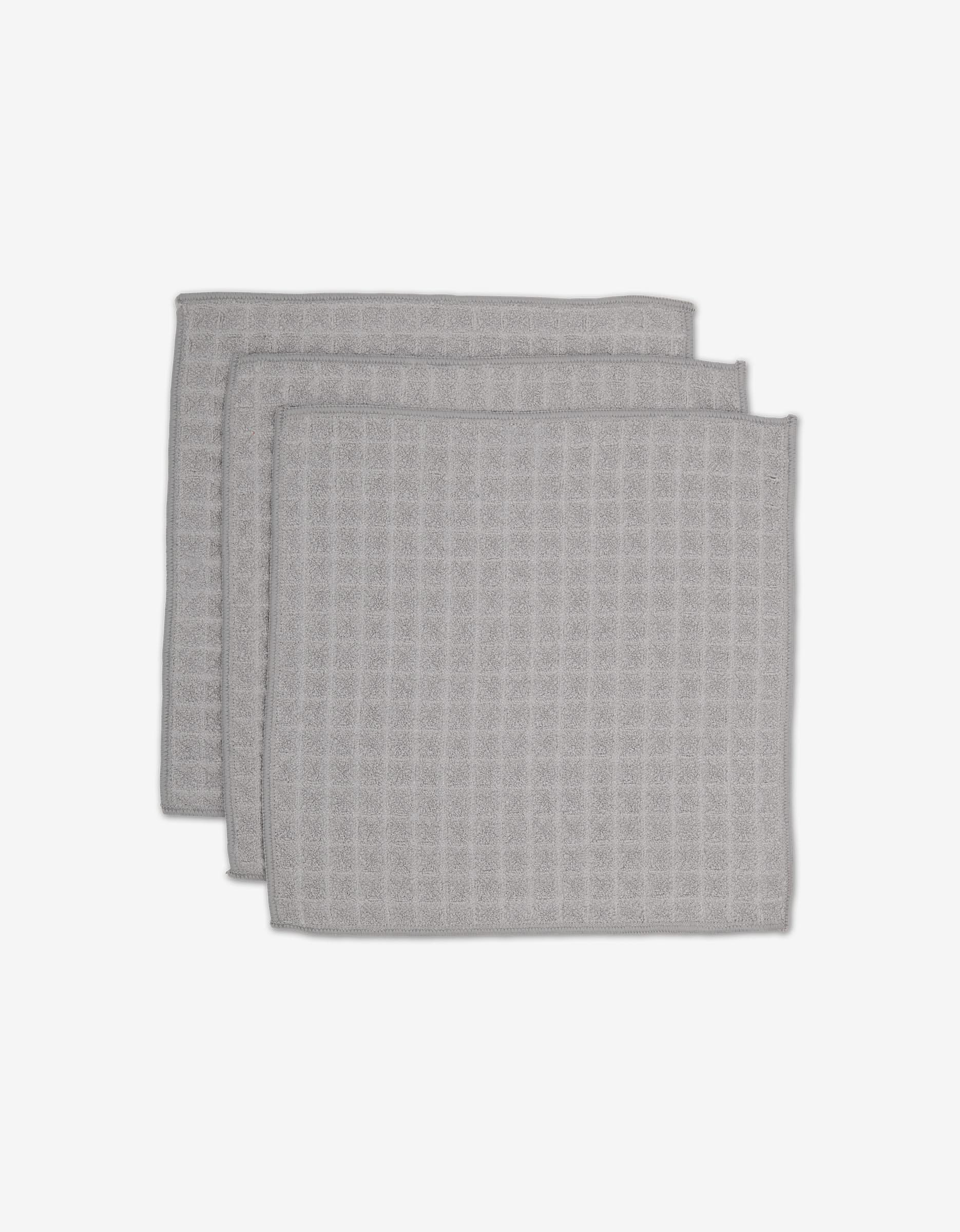 Three light gray GEOMETRY Stone Waffle Washcloths with a waffle texture are stacked slightly offset on a plain white background.