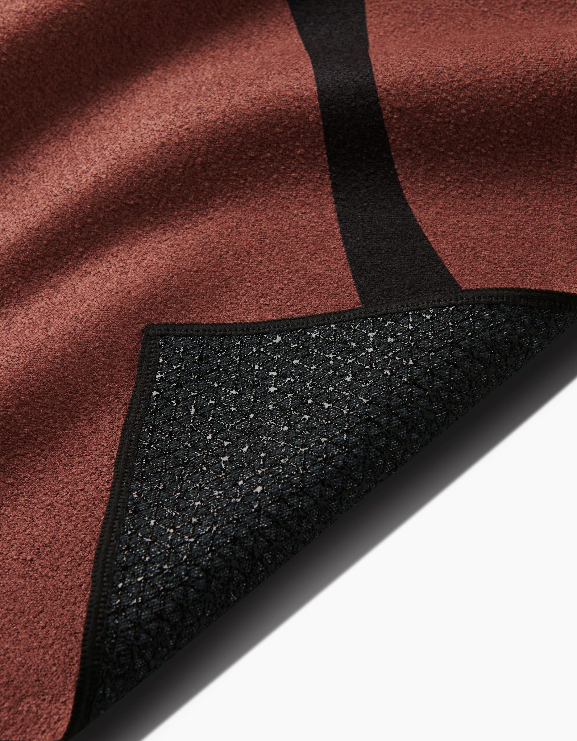 A close-up of the Cole Strem Black Swirl rug with a black edge, corner flipped to reveal its patterned black non-slip silicone grip backing for extra stability.