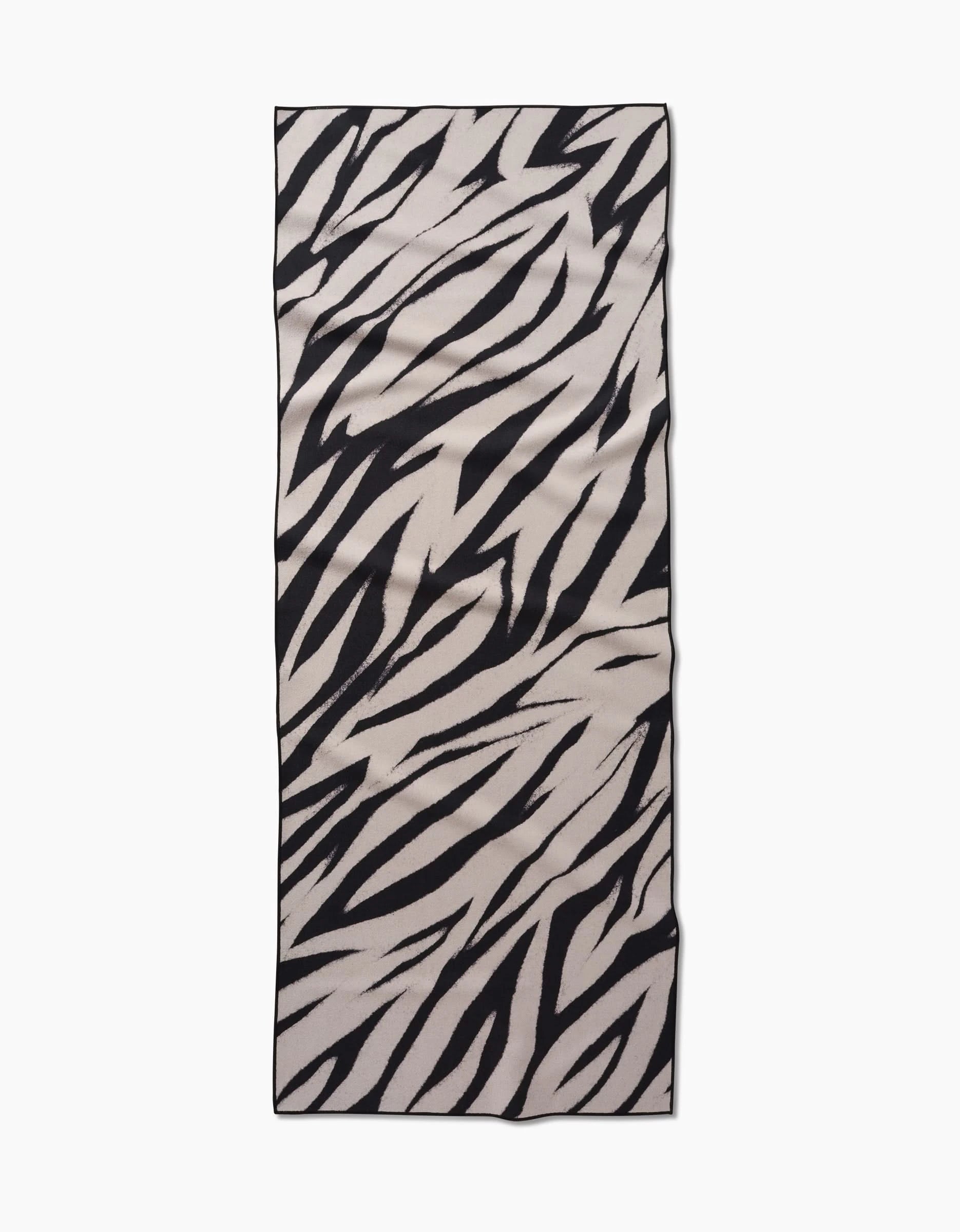 The GEOMETRY Chase yoga towel features a black and white zebra stripe pattern, crafted from recycled materials, displayed on a flat white background.