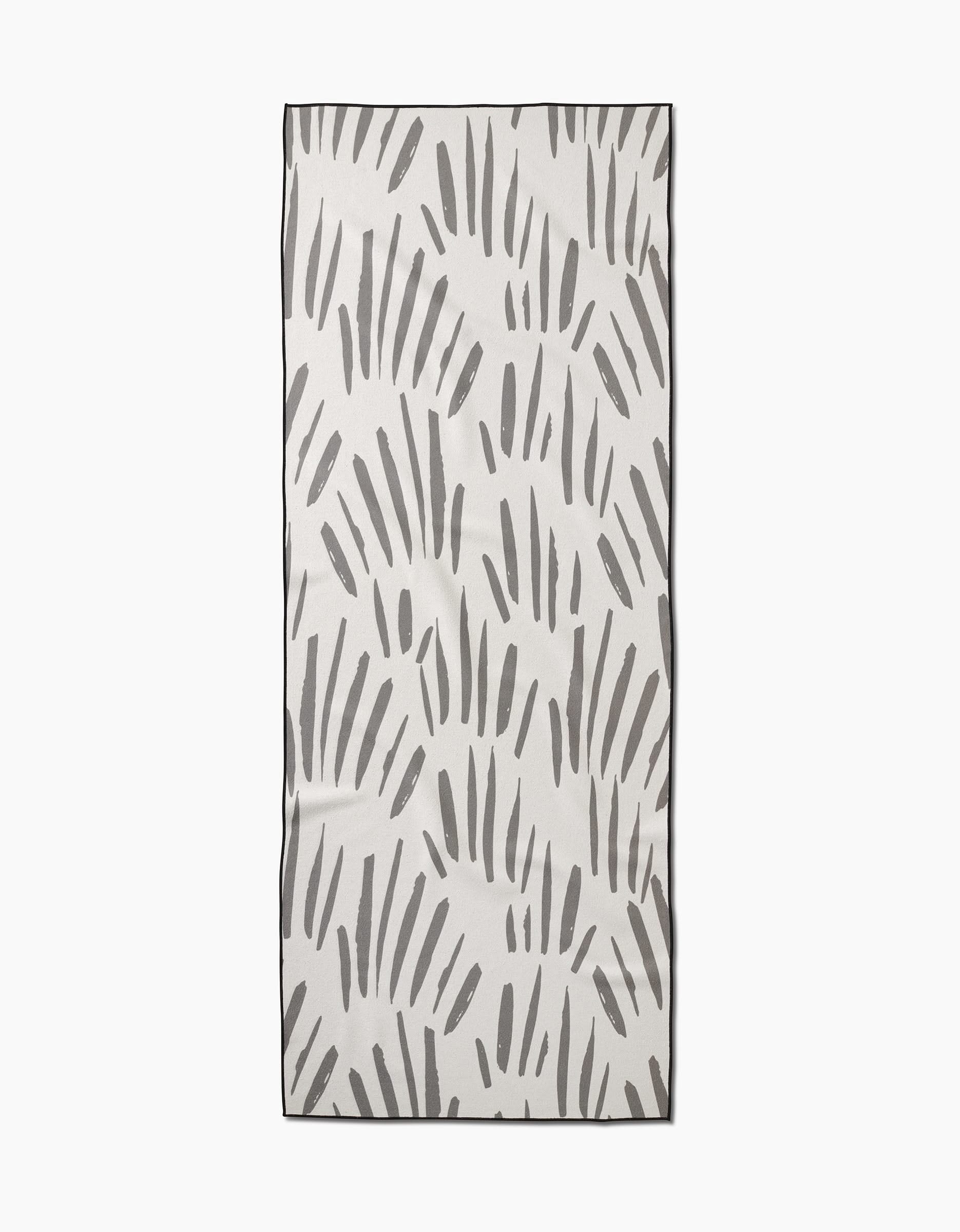 The Country Fields yoga towel by Hufton Studio is rectangular, white, and slip-resistant, featuring irregular vertical gray brush strokes scattered across its surface.
