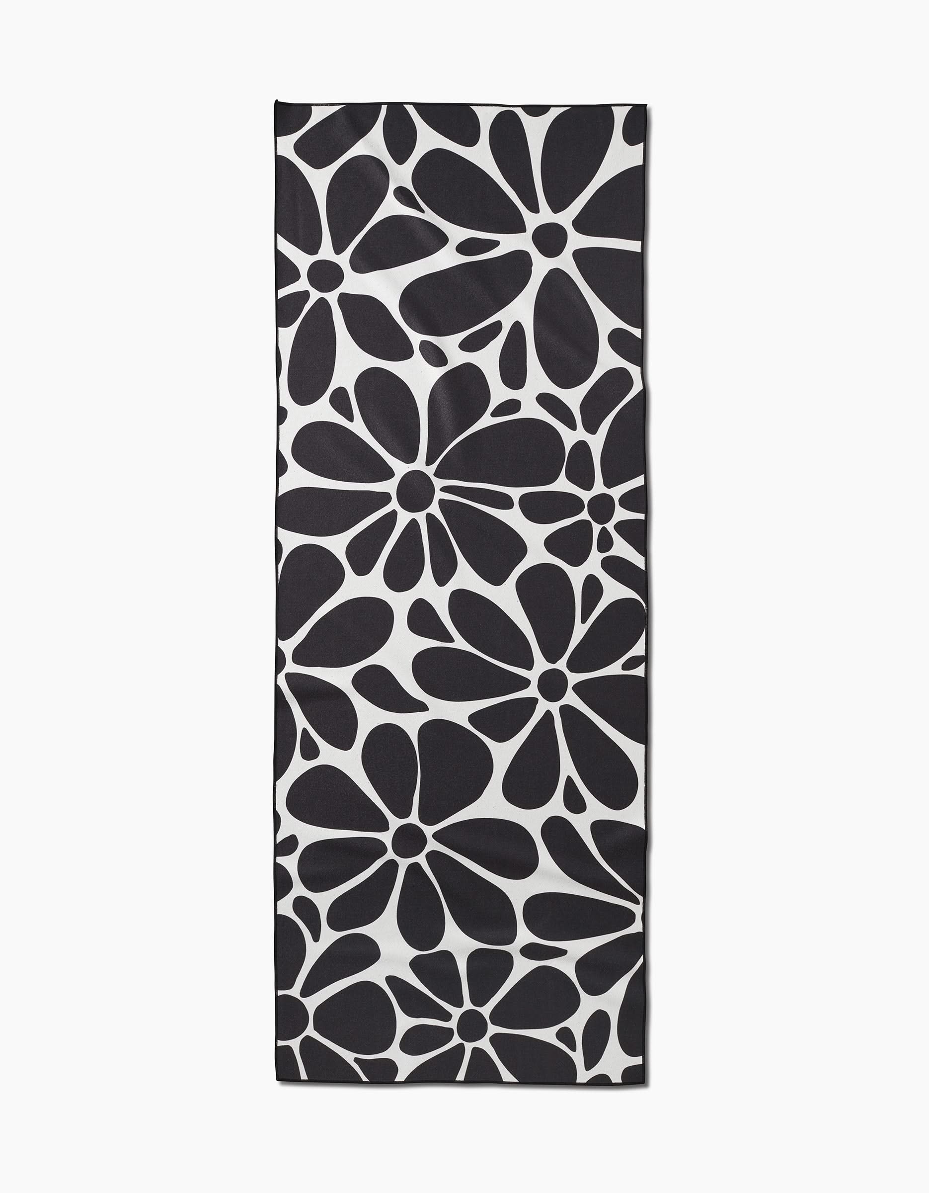 The GEOMETRY Cute Flowers yoga towel features a bold black and white abstract flower pattern on a white background. Made from recycled materials, its perfect for eco-conscious yogis who value style and sustainability.