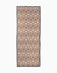 The Flower Patch yoga towel by Charlie Rowan Designs features a symmetrical geometric leaf pattern in brown and white squares with a thin black border and slip-resistant backing.