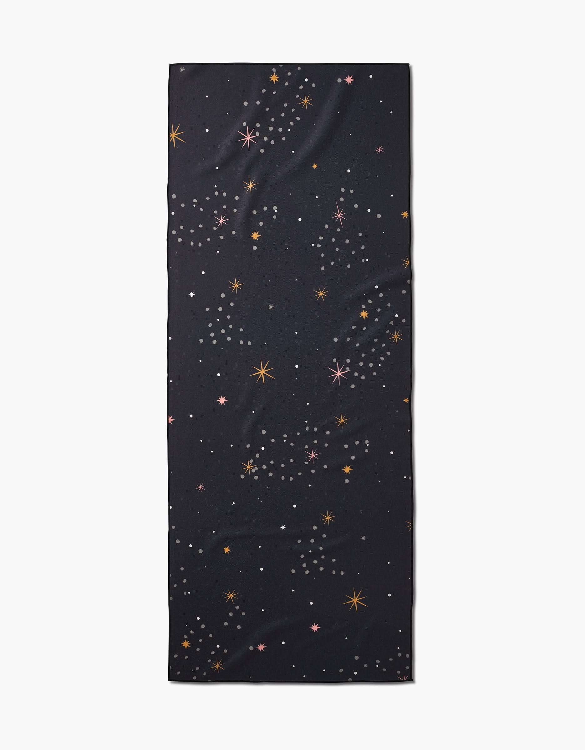 The Ash Cascade Galaxy Burst is a rectangular black recycled yoga towel featuring a multicolored scattered star pattern in orange, pink, and white, shown on a plain white background.