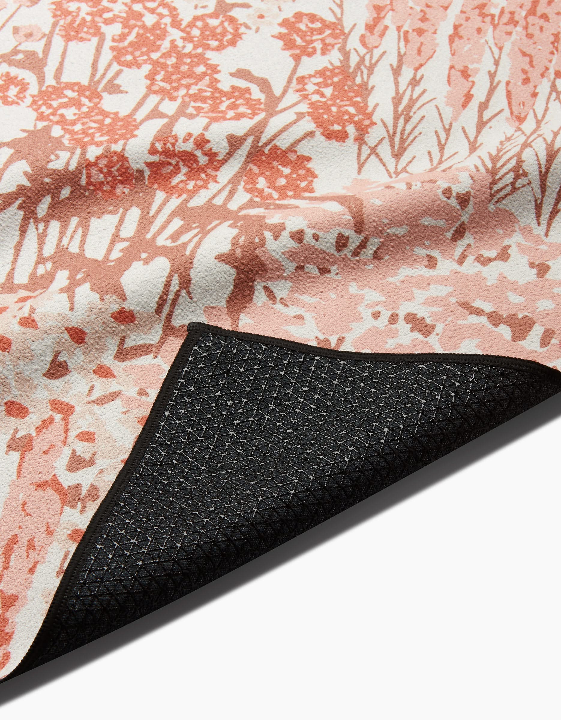 Close-up of Hufton Studios Garden Bloom yoga towel, featuring a pink and white floral pattern with black silicone non-slip backing visible at the corner.
