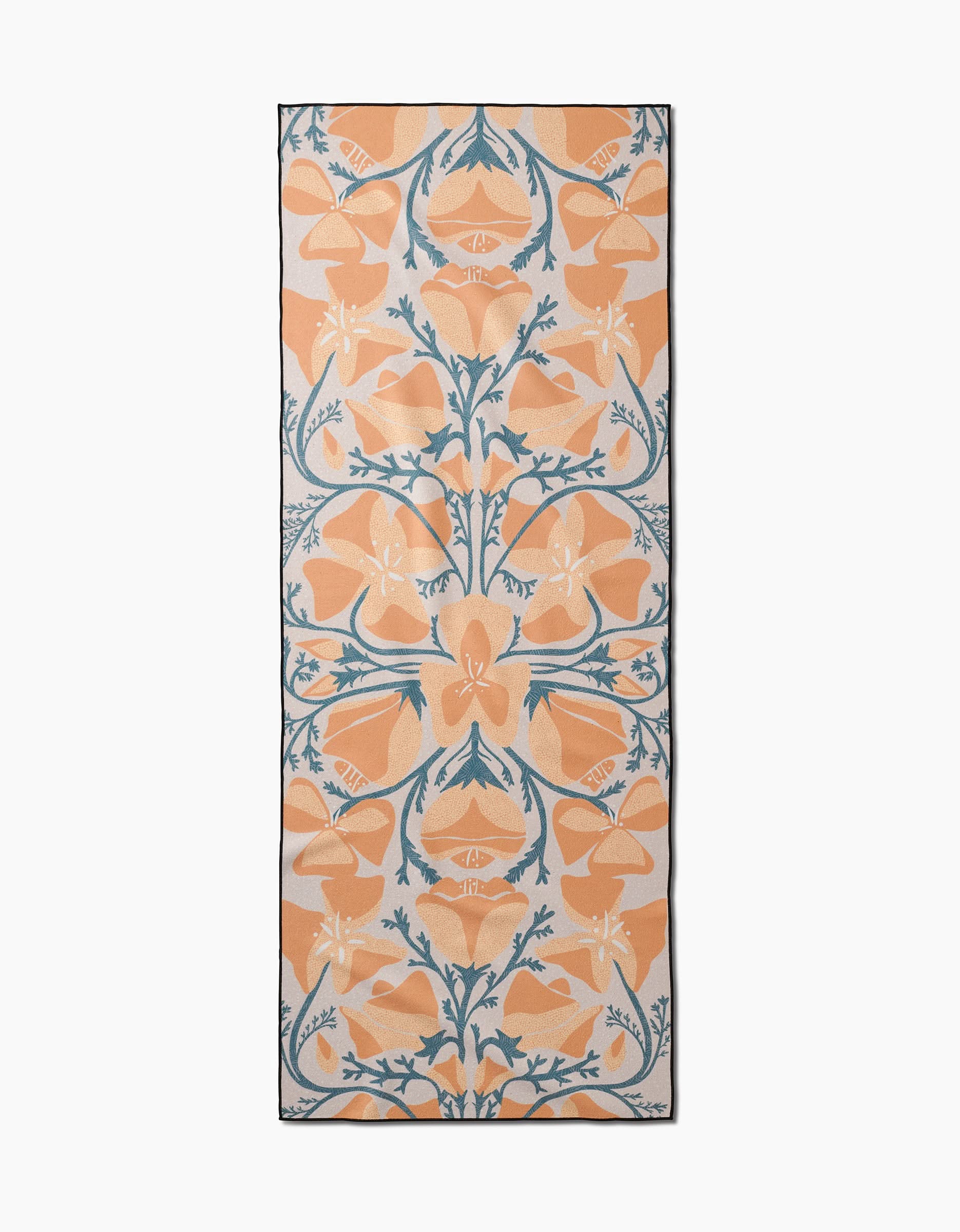 The Golden Poppy yoga towel by Julianne Haness features a rectangular, slip-resistant design with large orange flowers, green stems, and leaves on white—an ornate, symmetrical floral pattern that brings an artistic touch to your yoga routine.