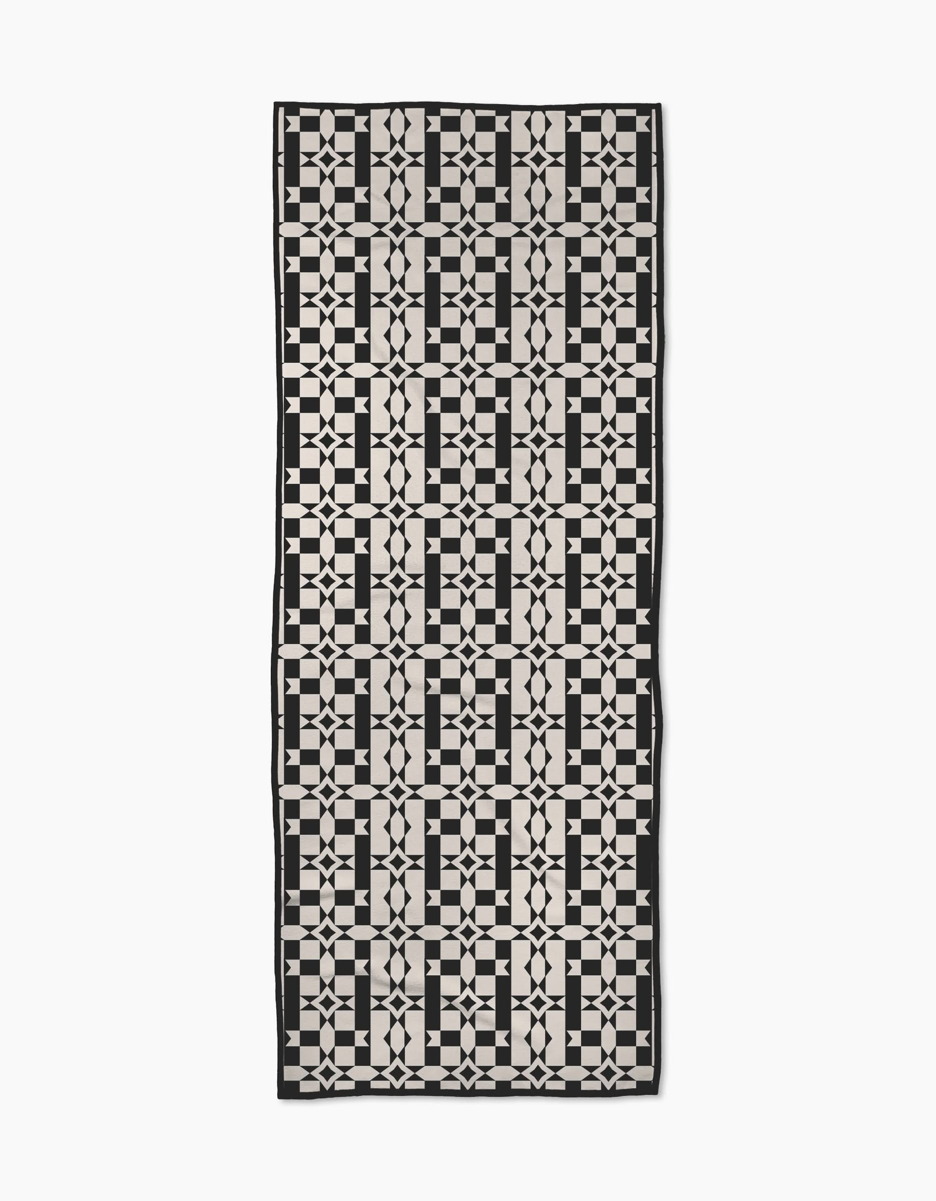 The Intermission yoga towel by Geometry features a black and white geometric pattern of squares, circles, and lines, crafted from recycled materials for a modern, sustainable design.