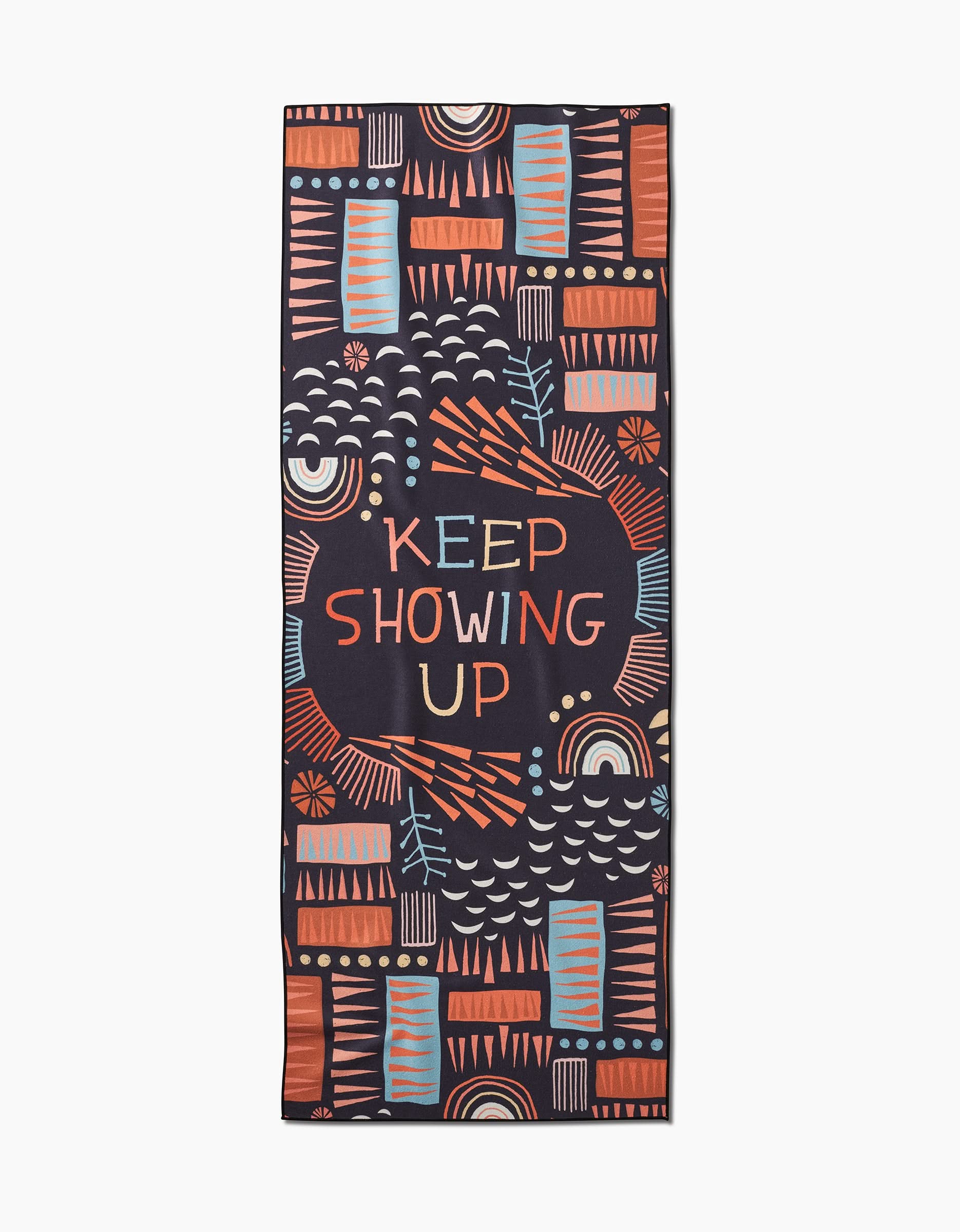The Keep Showing Up yoga towel by Jessica Swift features a rectangular, slip-resistant design with bold geometric shapes in orange, blue, and peach, plus the phrase KEEP SHOWING UP prominently at the center.