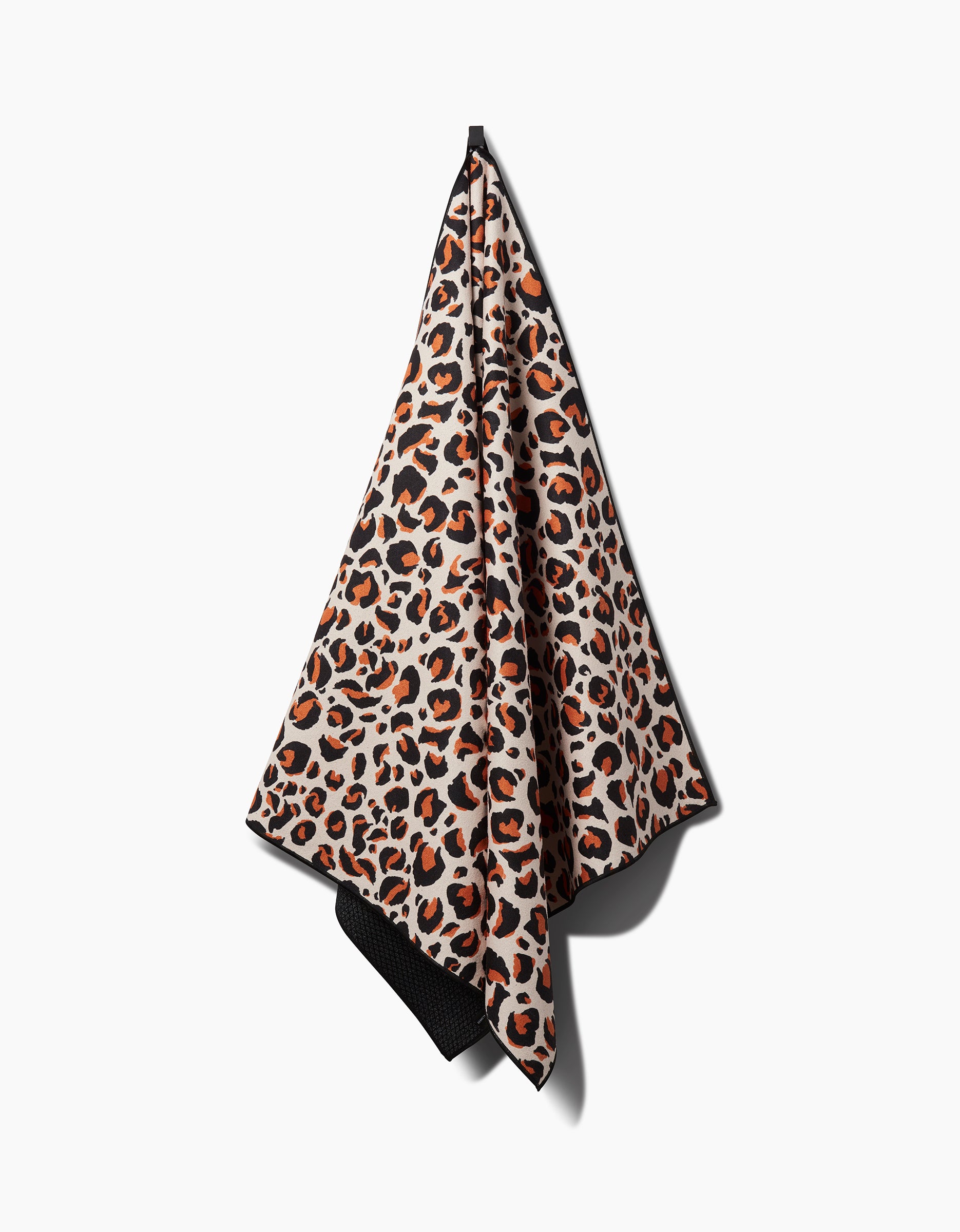 The GEOMETRY Leopard hanging yoga towel features a bold brown, black, and tan leopard print, made from recycled materials and shown on a plain white background.