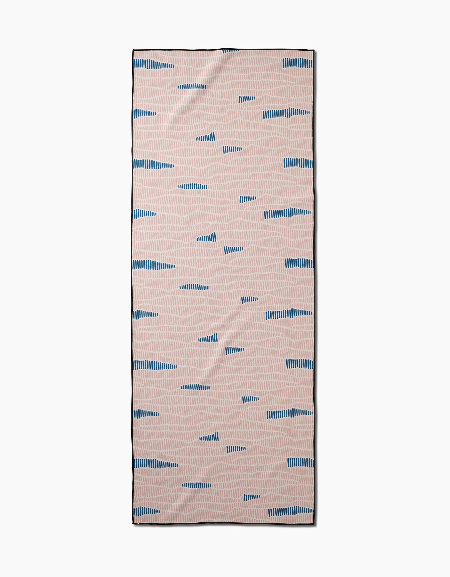 The Twig + Spark Ridgeline is a rectangular, slip-resistant yoga towel featuring a light beige background adorned with an abstract pattern of short, irregular blue lines and dashes scattered across the surface.