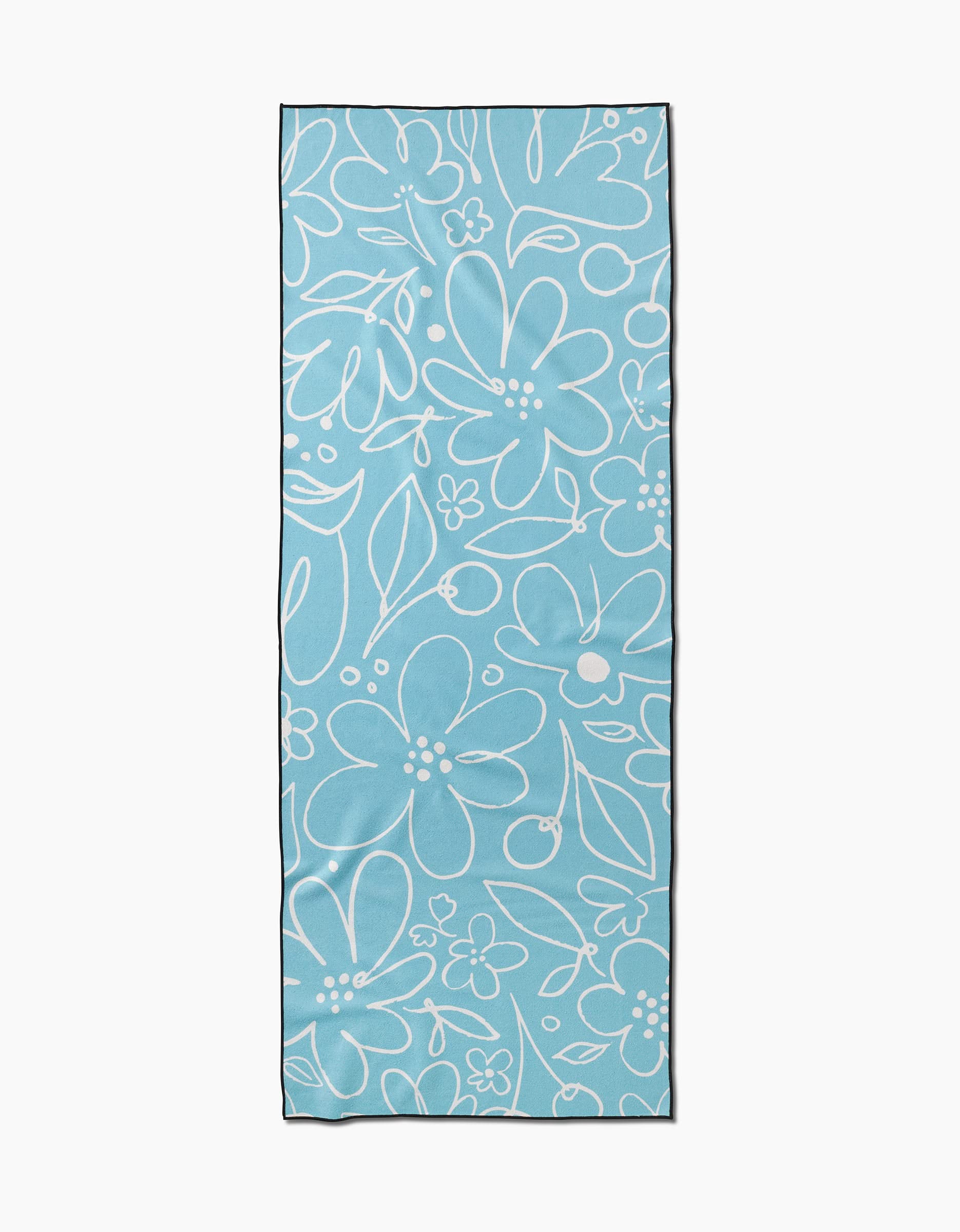 The Sara Mari River Blossom yoga towel is rectangular and light blue, made from recycled materials with an all-over white outlined floral and leaf design.