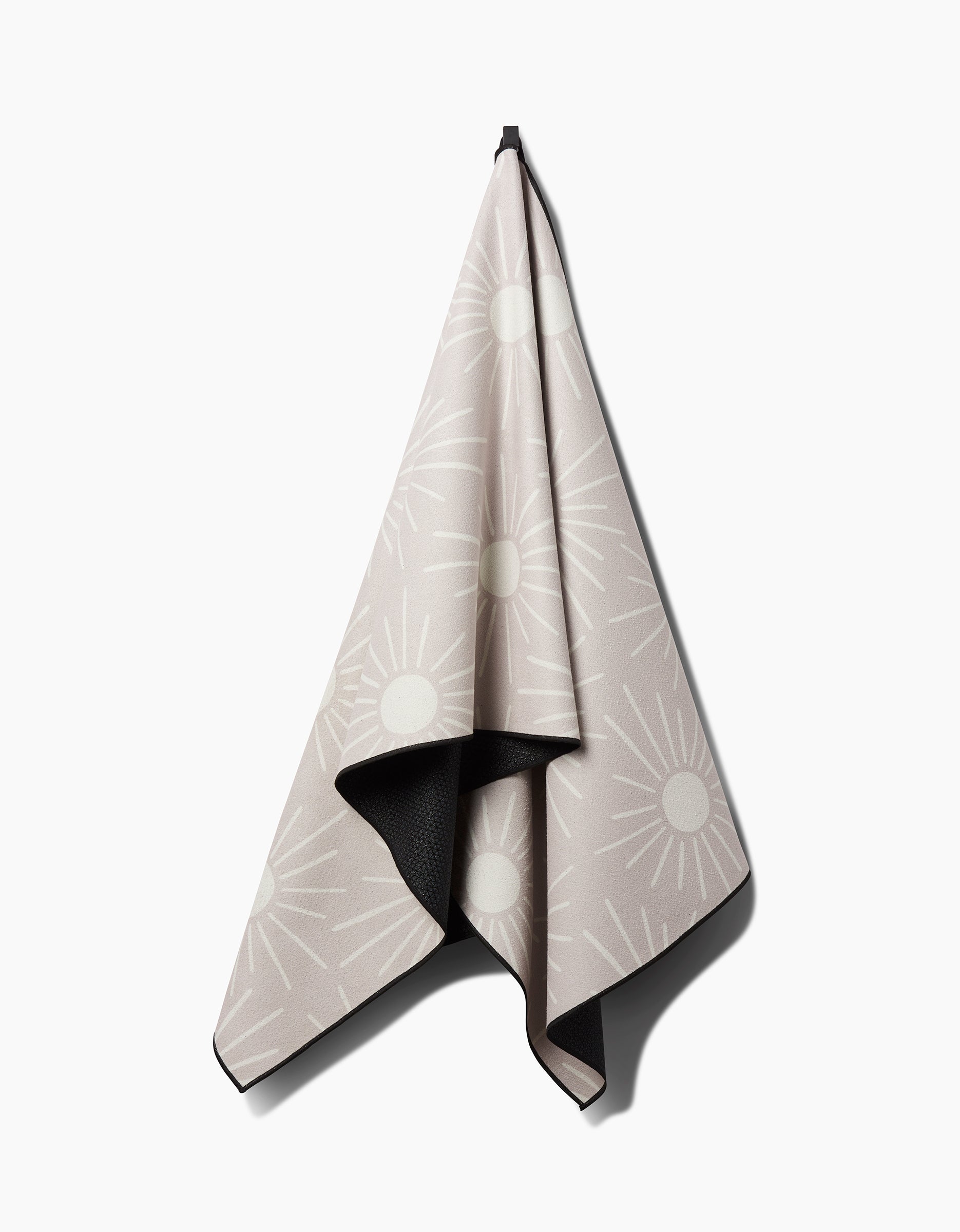 The Hufton Studio Sunny Geo yoga towel features a beige front with a white sunburst pattern and a dark reverse side, offering stylish contrast—ideal as an eco-conscious, recycled option for your yoga practice.