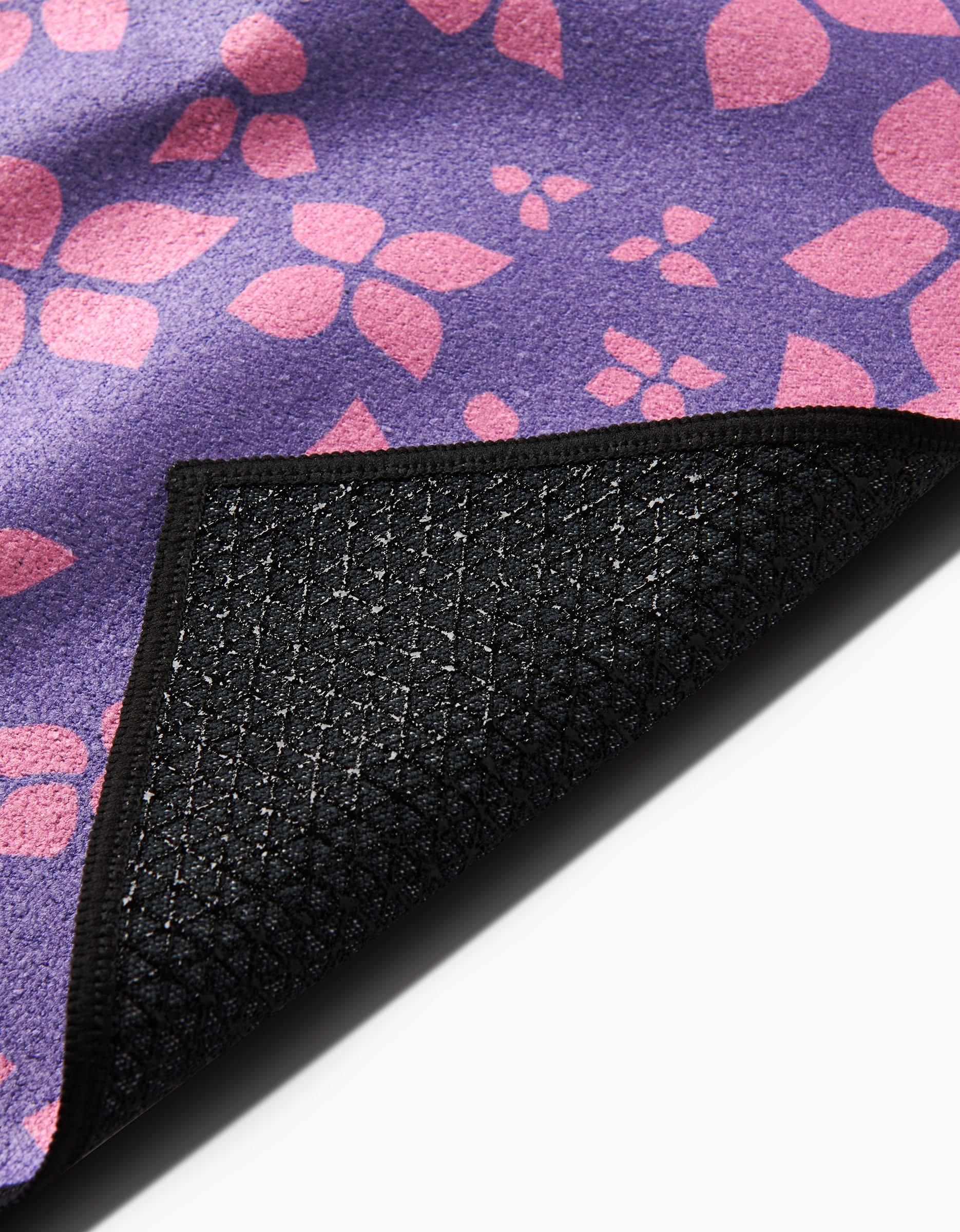 Close-up of Sareka Uniques You Give Me Butterflies yoga towel, featuring a purple and pink floral top and a black silicone grip, non-slip underside. One corner is folded to show both surfaces.