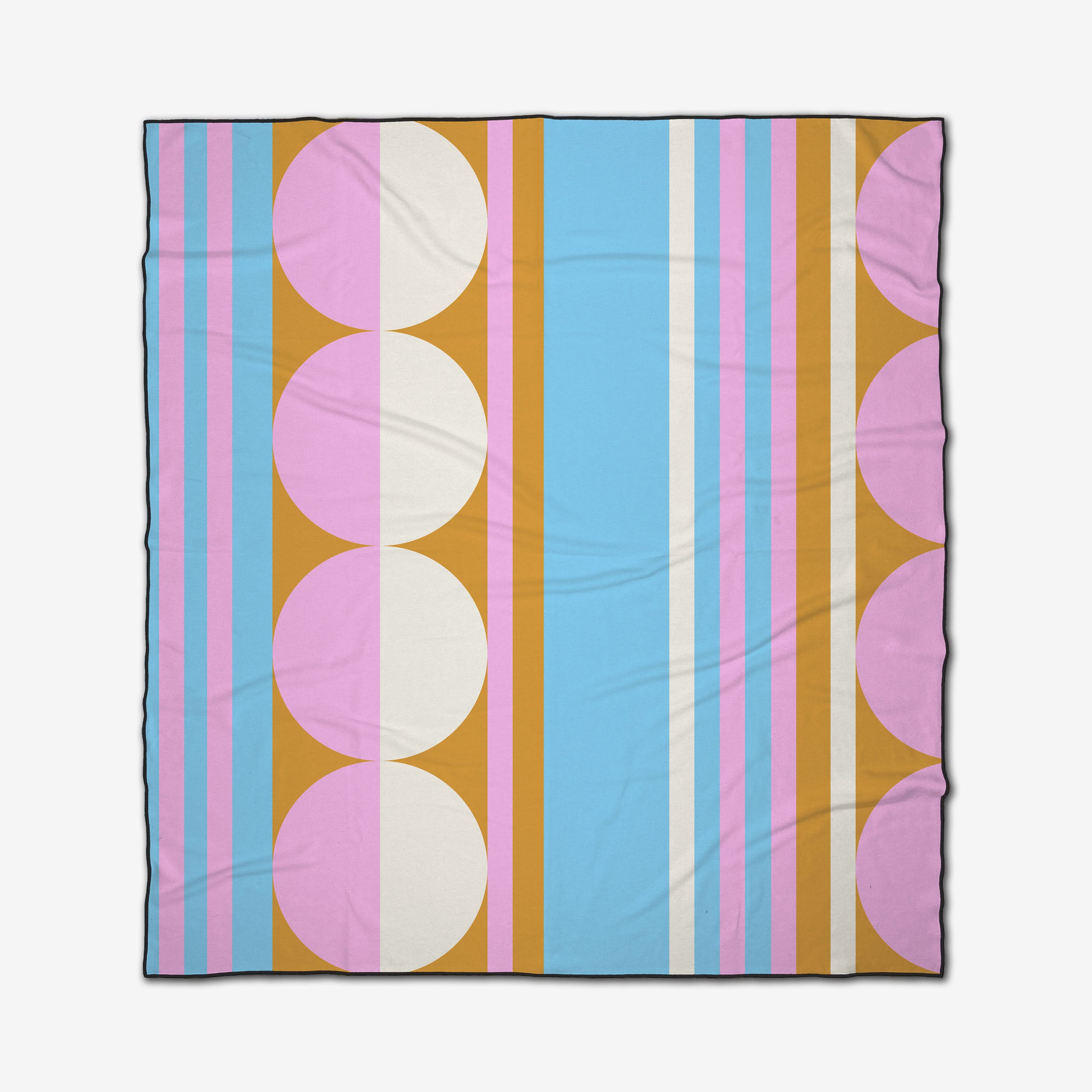 The GEOMETRY Turmeric Pinks beach blanket is quick-drying, with a geometric pattern of blue, pink, orange, and white vertical stripes accented by large pink and white circles along the edges.