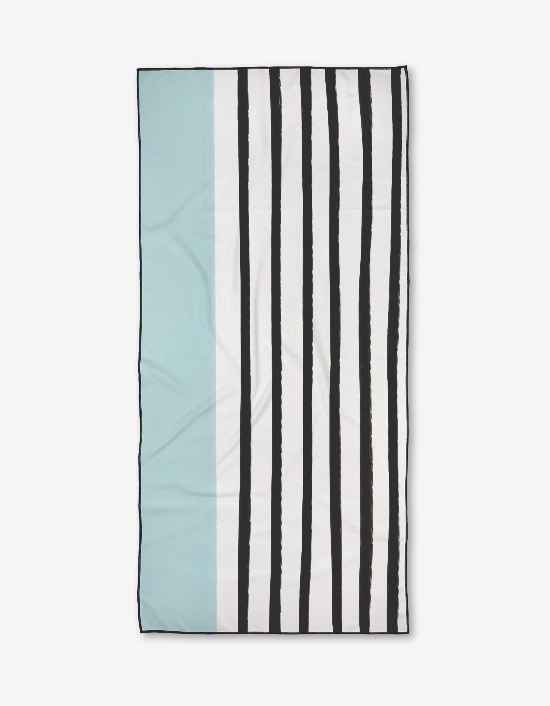 The Brooks Micro-loop Beach Towel by Kailee Wright features a light blue section on the left, a thin white stripe, and uneven black vertical stripes on a white background—crafted from recycled materials.