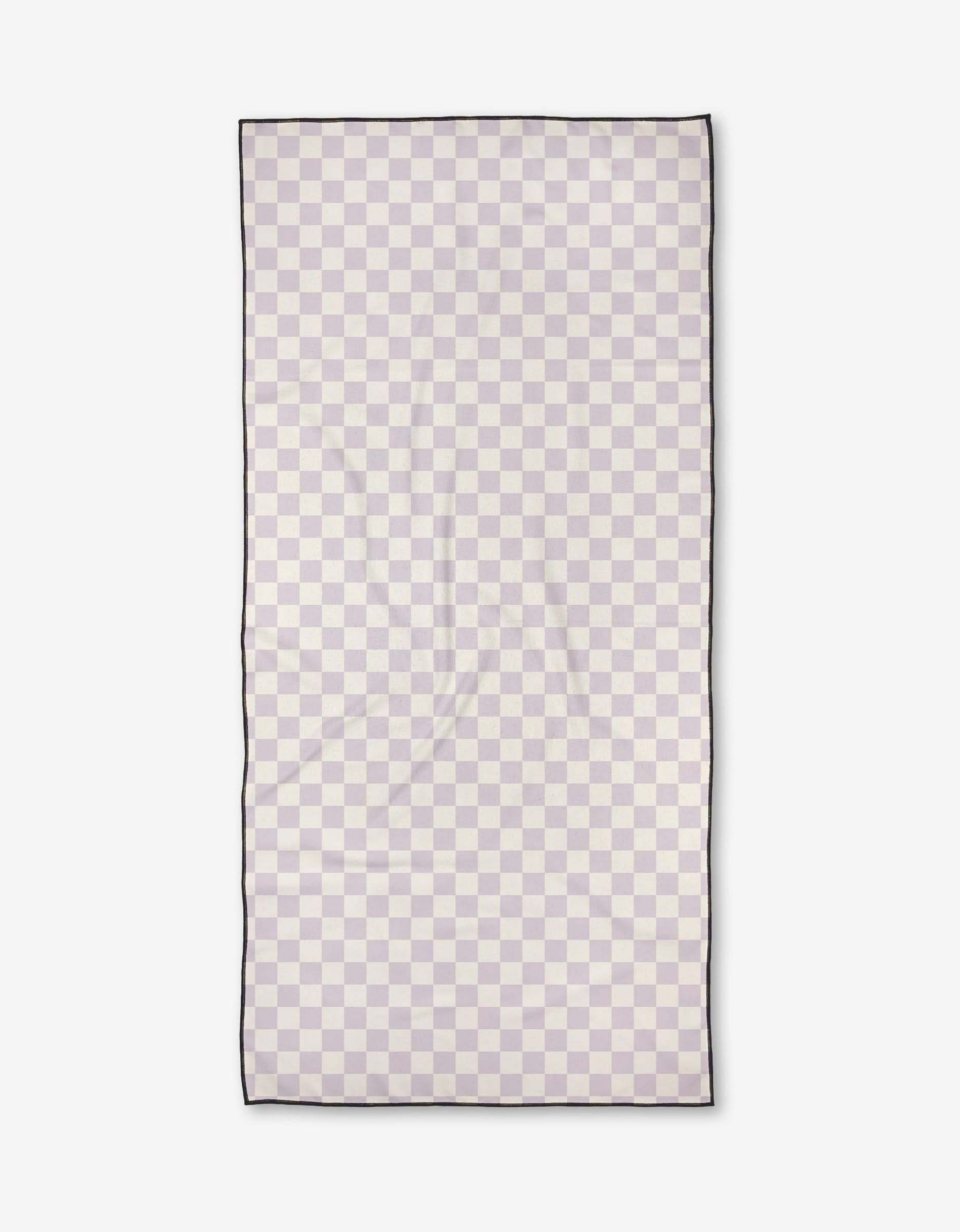 The Check Please Beach Towel by Kelsi Fullmer features a rectangular geometric checkerboard in light beige and pale gray, thin black edging, and is made of quick-drying, recycled materials. Shown flat on a white background.