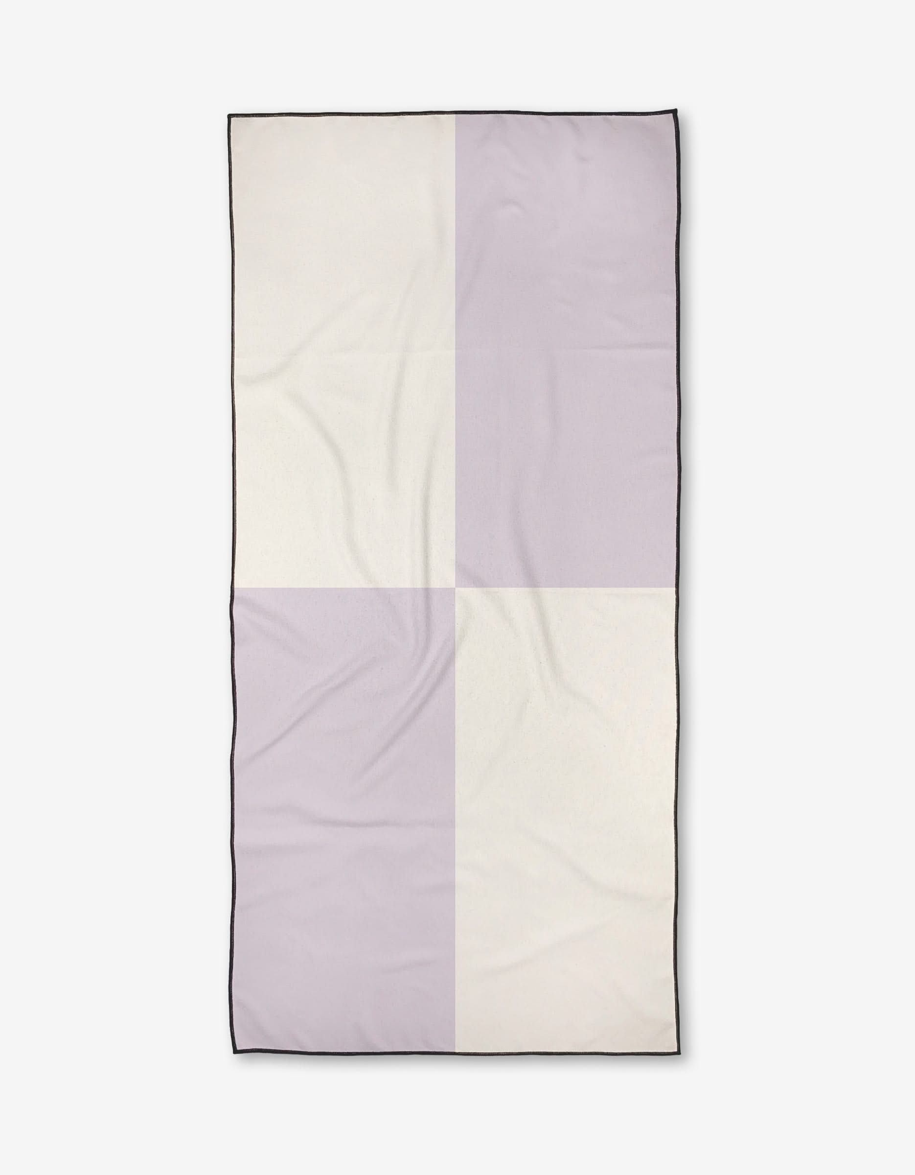 The Kelsi Fullmer Four Square is a rectangular, quick-drying Micro-loop Beach Towel in light beige and pale lavender checkerboard with a thin black edge. Made from recycled materials, it features slight wrinkles and is shown flat on white.