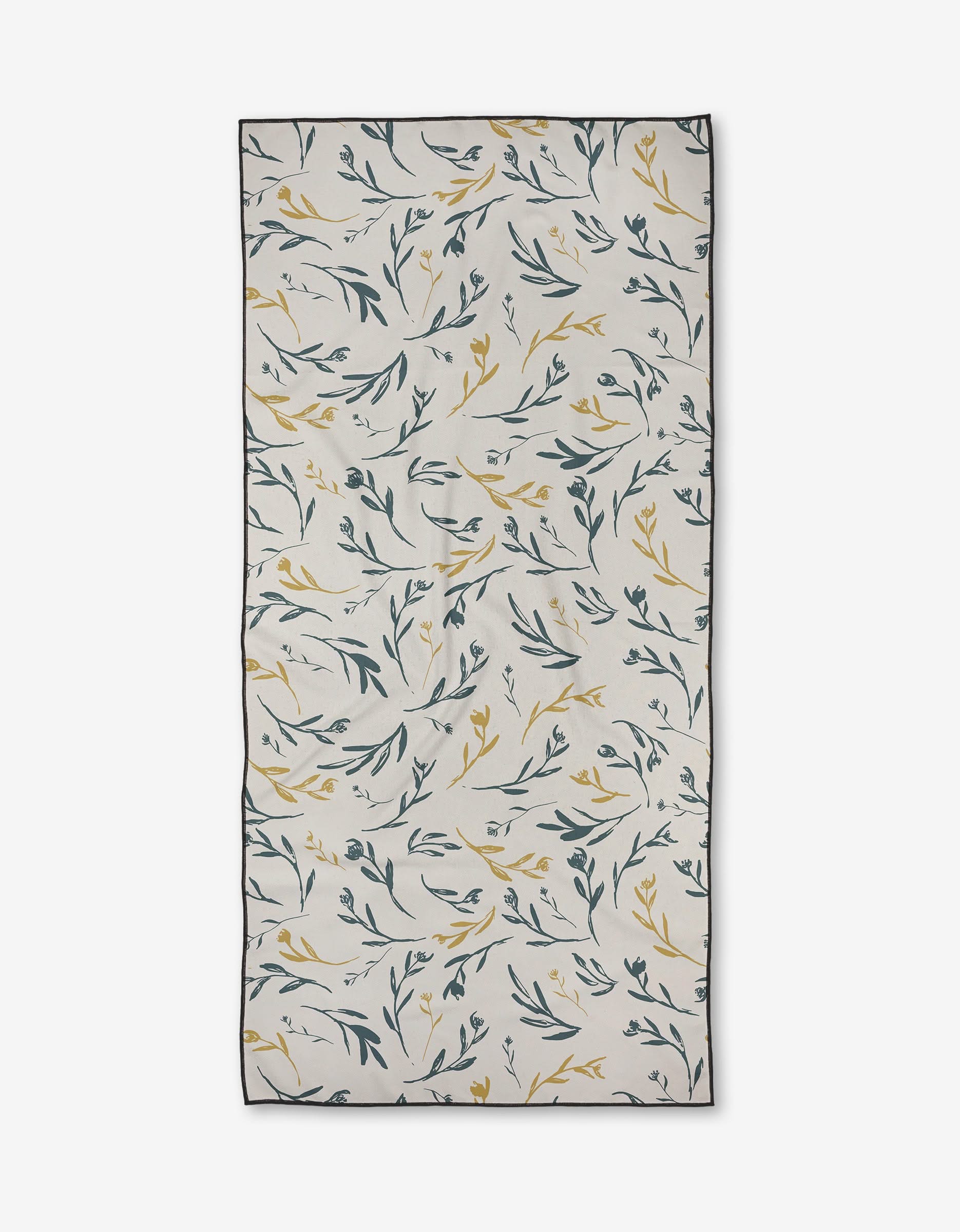 The Meander beach towel by Toboggan Avenue features green and yellow leafy branches on a white background, black-outlined edges, and natural folds. Made from recycled materials, this towel is quick-drying and rectangular in shape.