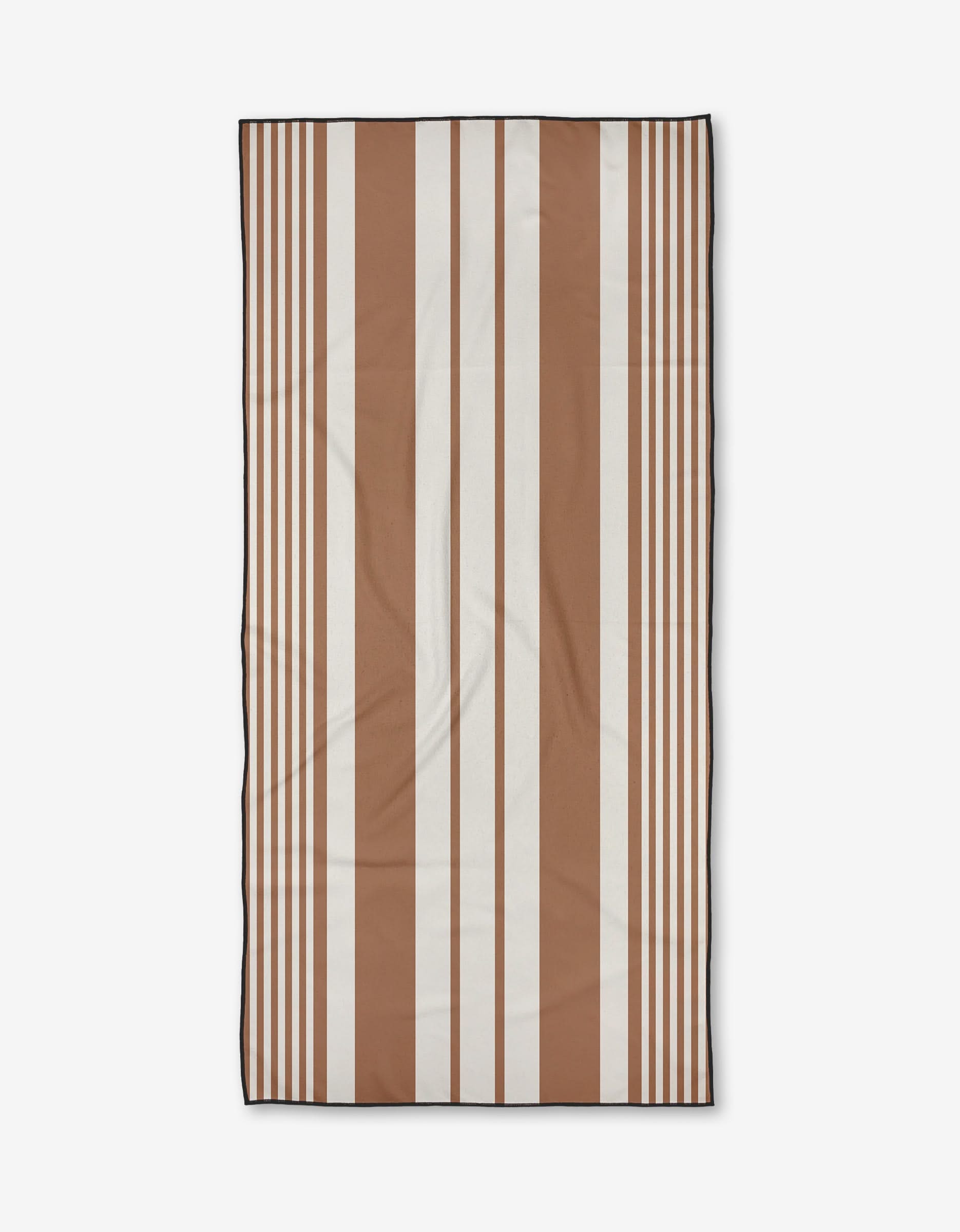 The Reina beach towel by Becki Owens features alternating wide and narrow vertical stripes in brown and white on a plain background, and is crafted from quick-drying recycled materials.