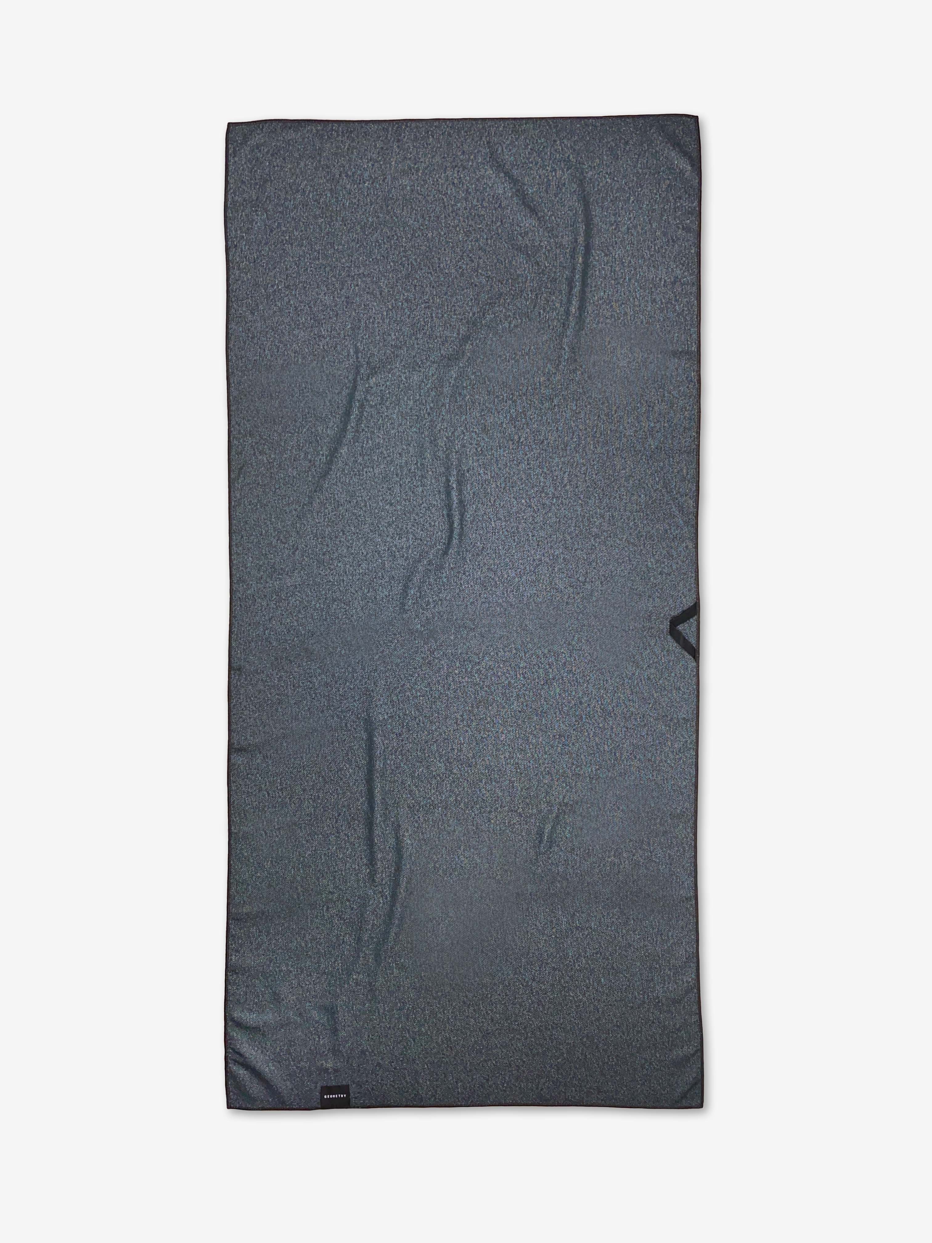 The Ash Cascade Lakeside Bloom is a dark gray rectangular micro-loop beach towel with subtle texture and slight wrinkles, crafted from recycled materials and shown laid flat on a white background.