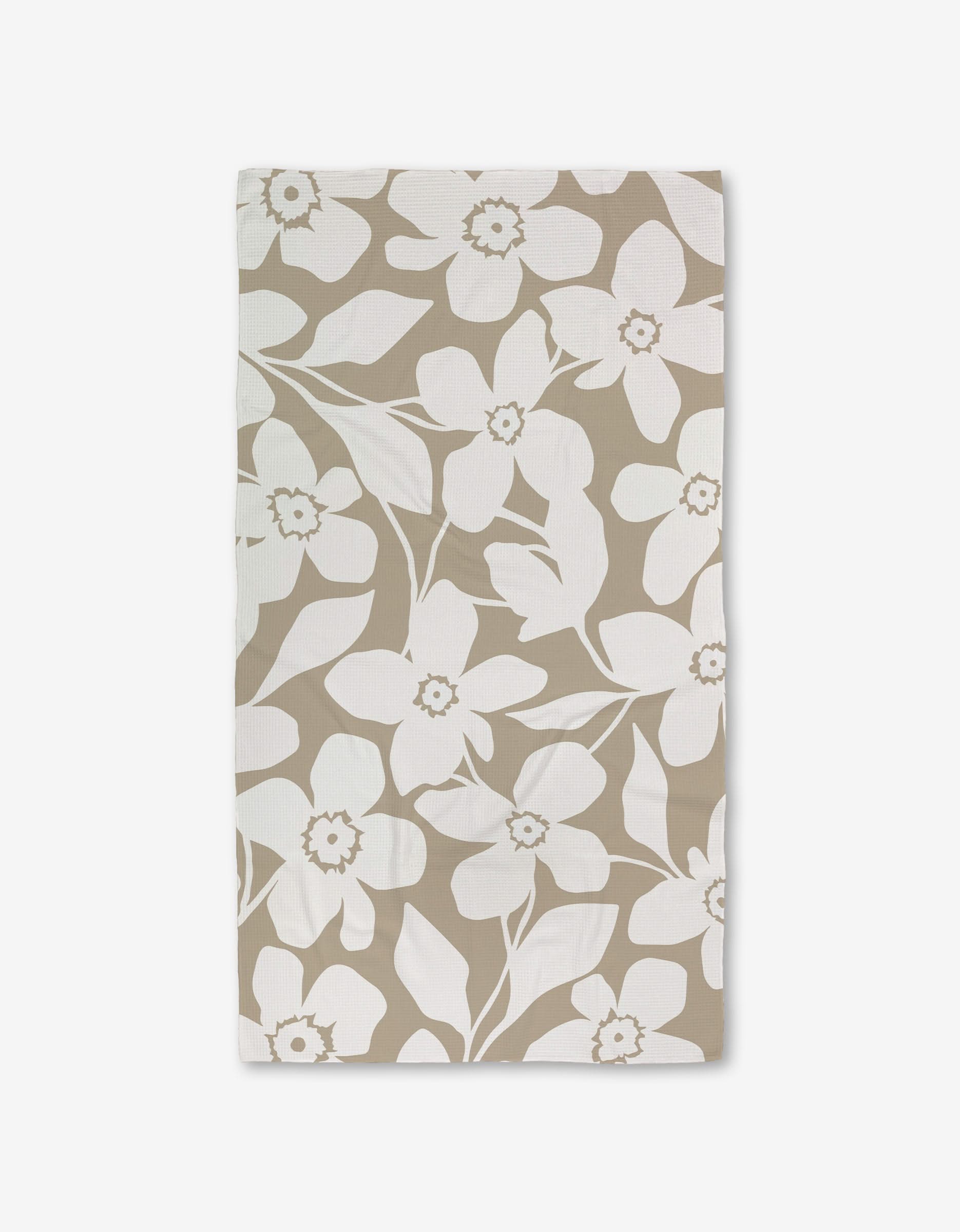 A GEOMETRY Big Tan Flowers Luxe Bath Towel, featuring a white floral pattern of large flowers and leaves made with Geoweave technology, is shown flat on a white background.