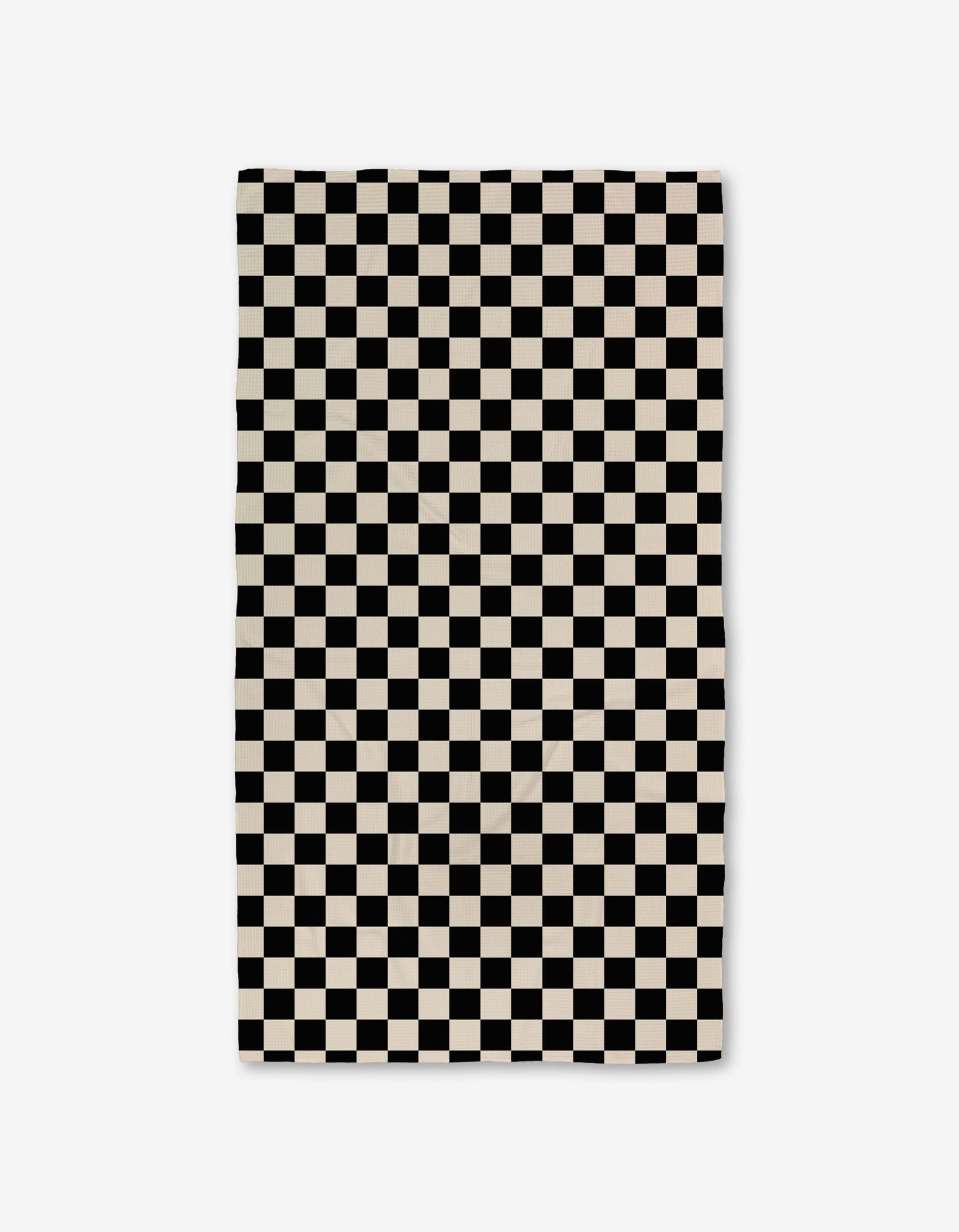 The GEOMETRY Checkered Luxe Bath Towel, featuring Geoweave technology and a black-and-white checkerboard pattern, offers an ultra-absorbent experience against a crisp white background.