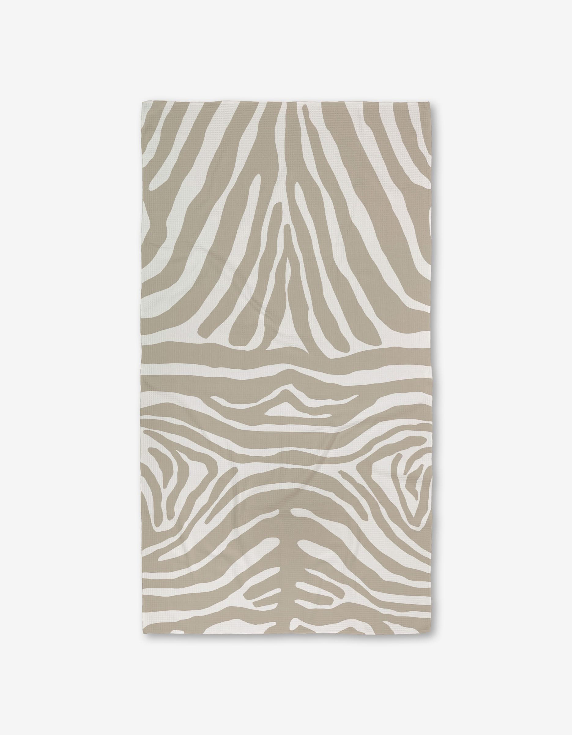 The GEOMETRY Zen Zebra bath towel, featuring a beige and white zebra stripe pattern and crafted with Geoweave technology for superior absorbency, is shown flat on a white background.