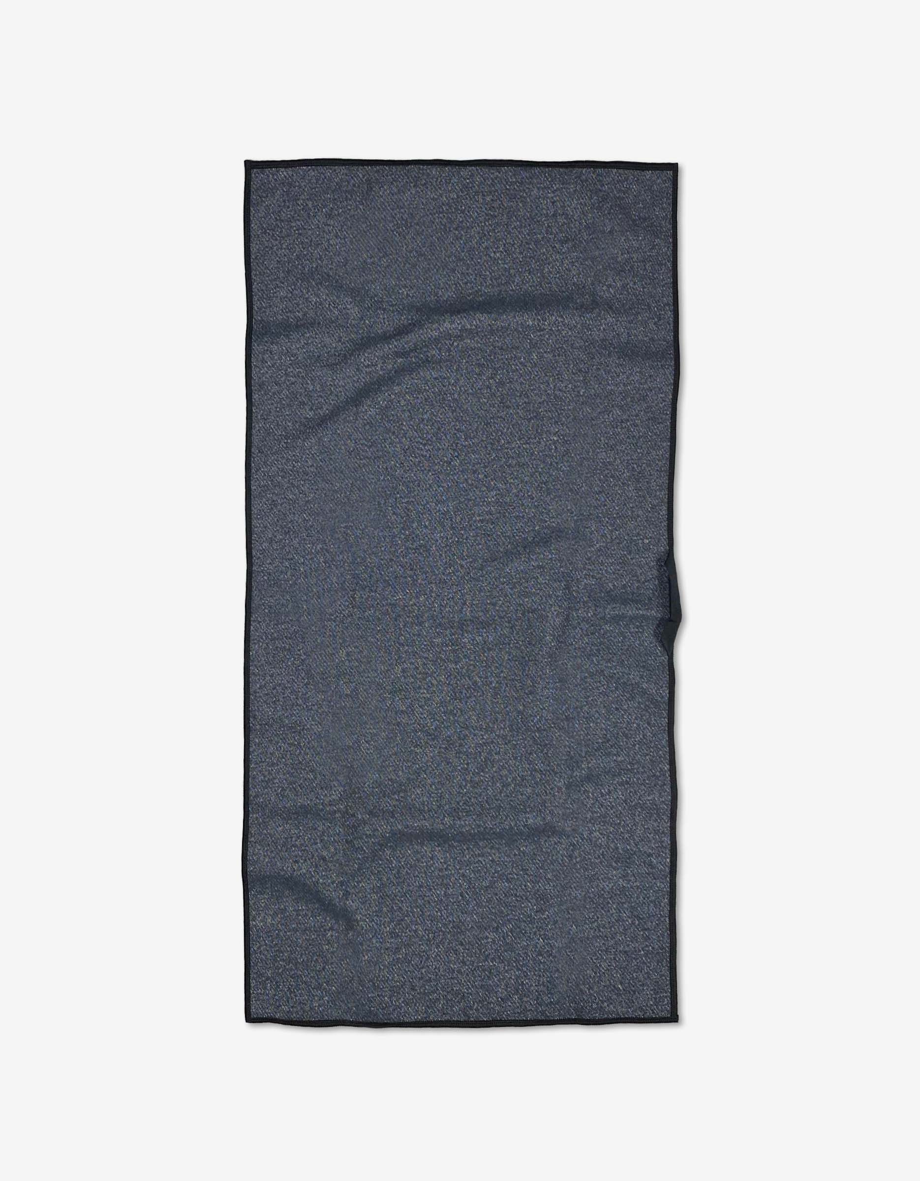 The Ashley Guarrasi Powder Puff, a rectangular dark gray fitness towel made from recycled materials, is laid flat on a white background, displaying subtle texture and slight creases.