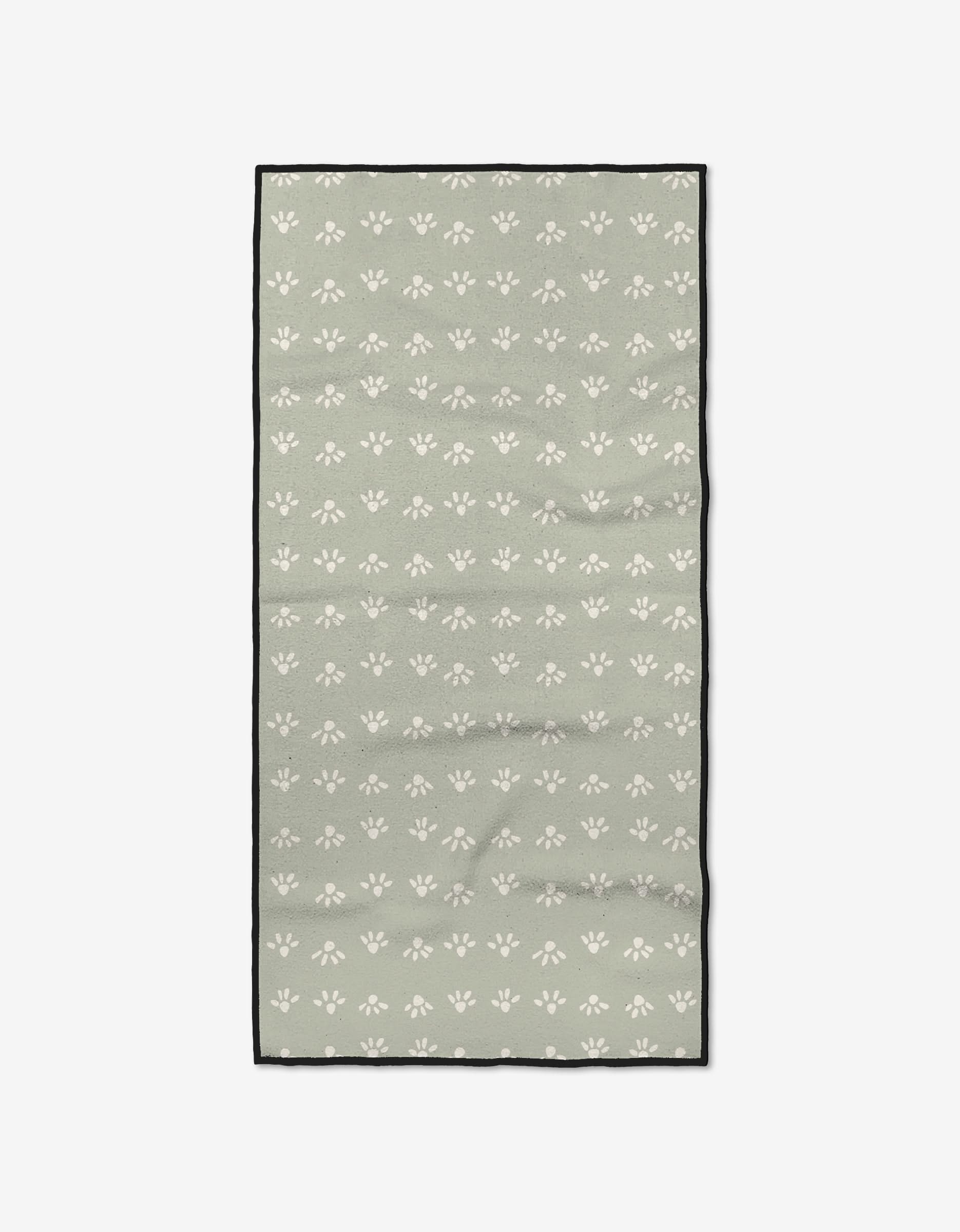The Sun Bursts by Anee Shah is a rectangular, sage green fitness towel made from recycled materials, patterned with small white paw prints and finished with a slim black border.