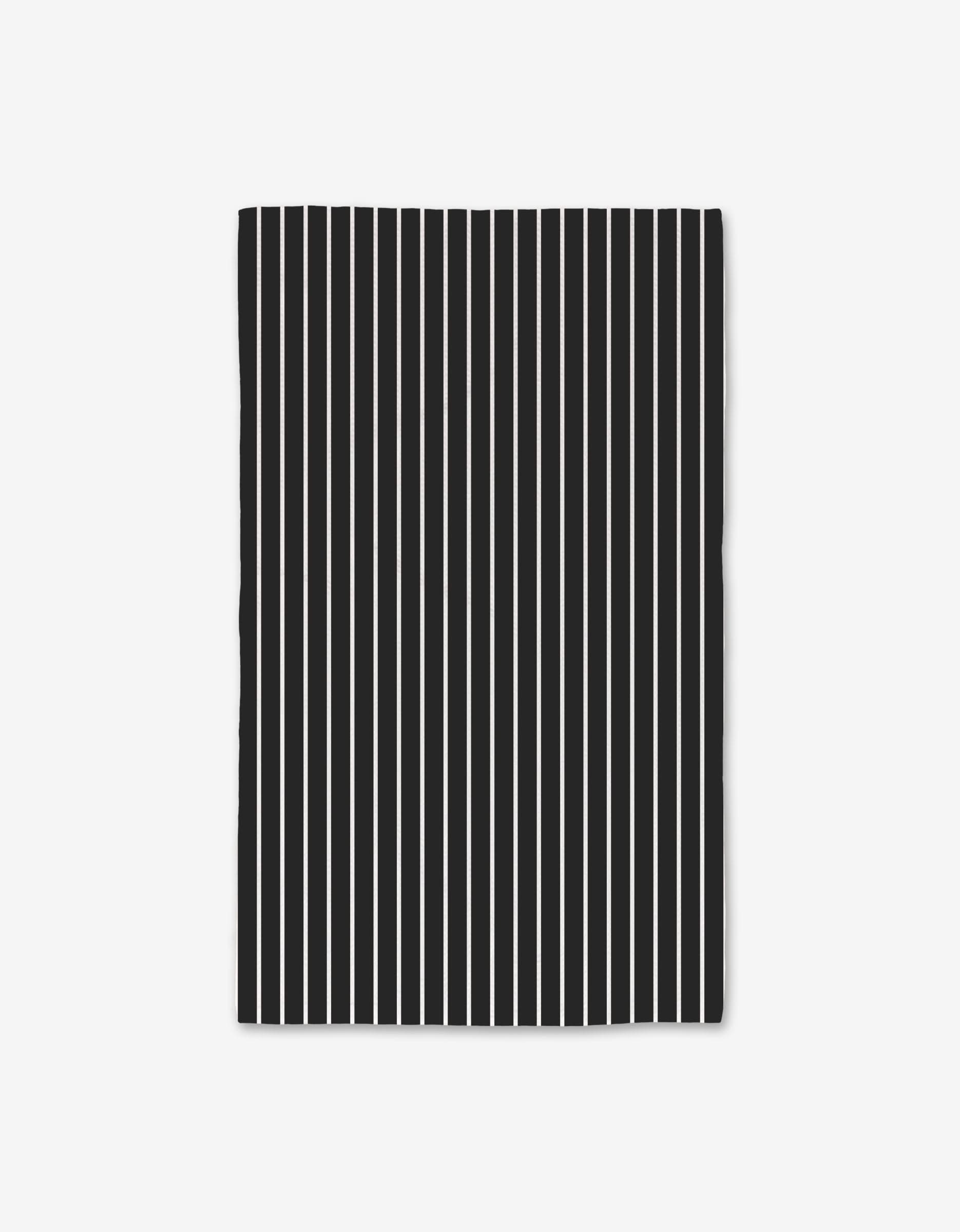 The GEOMETRY Black Linen is a rectangular black cloth crafted from recycled materials, featuring evenly spaced vertical white stripes for a simple and bold look against a light background.