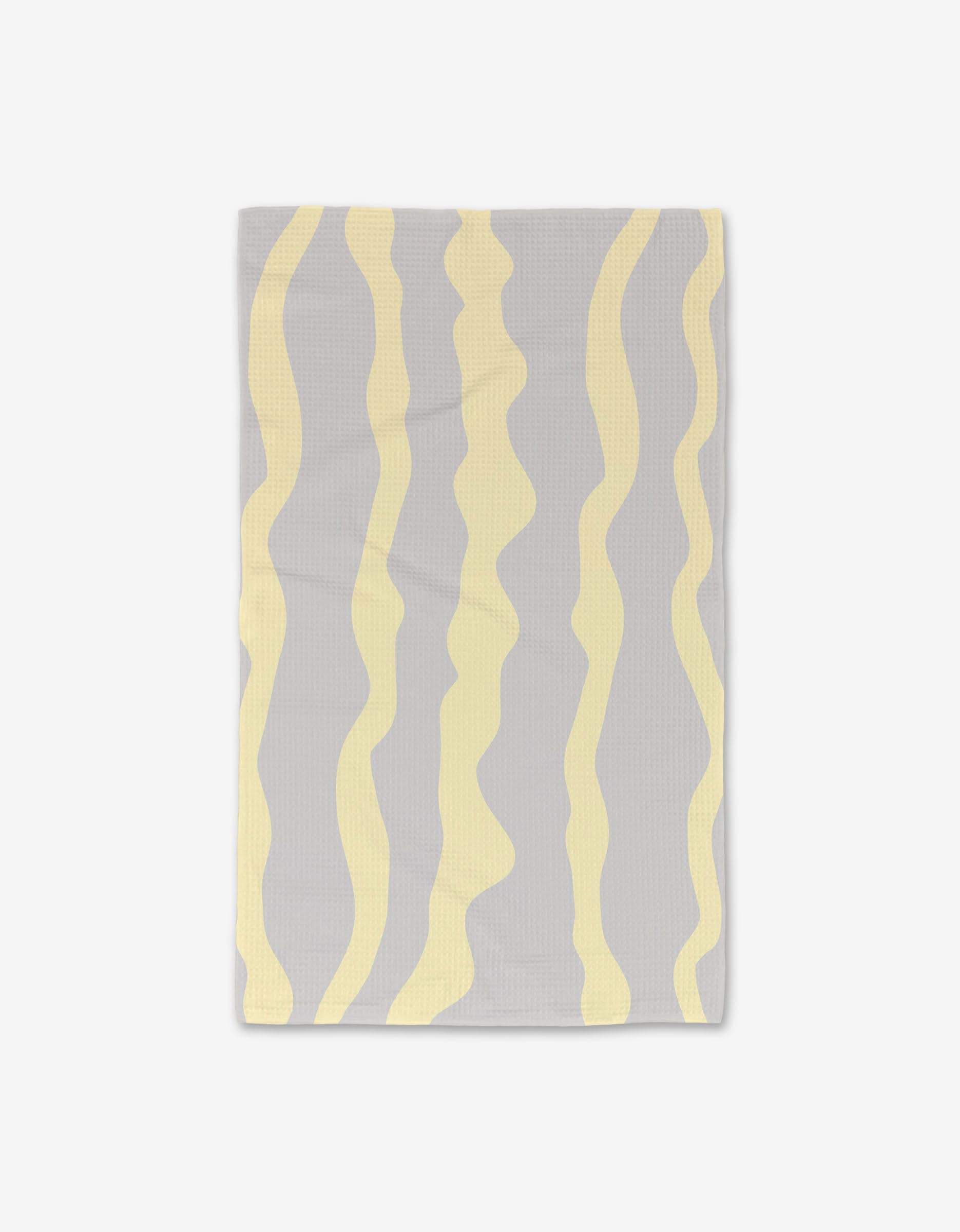 The GEOMETRY Eclipse Twist is a rectangular gray towel with evenly spaced, wavy vertical yellow stripes. This ultra-absorbent Luxe Hand Towel is shown laid flat on a white background.