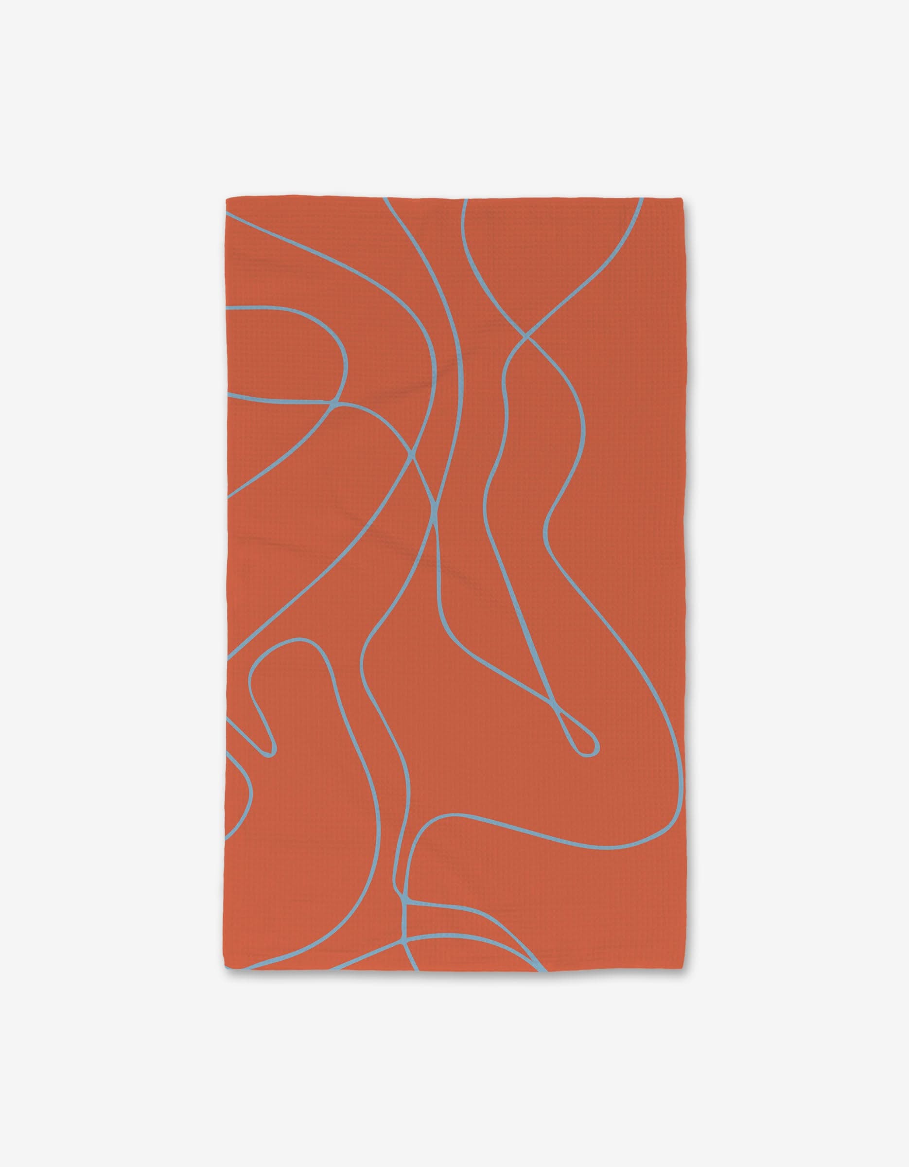 The GEOMETRY Energetic Orange hand towel is rectangular, burnt orange, and made from recycled materials, featuring thin wavy light blue abstract lines across its surface and displayed against a white background.