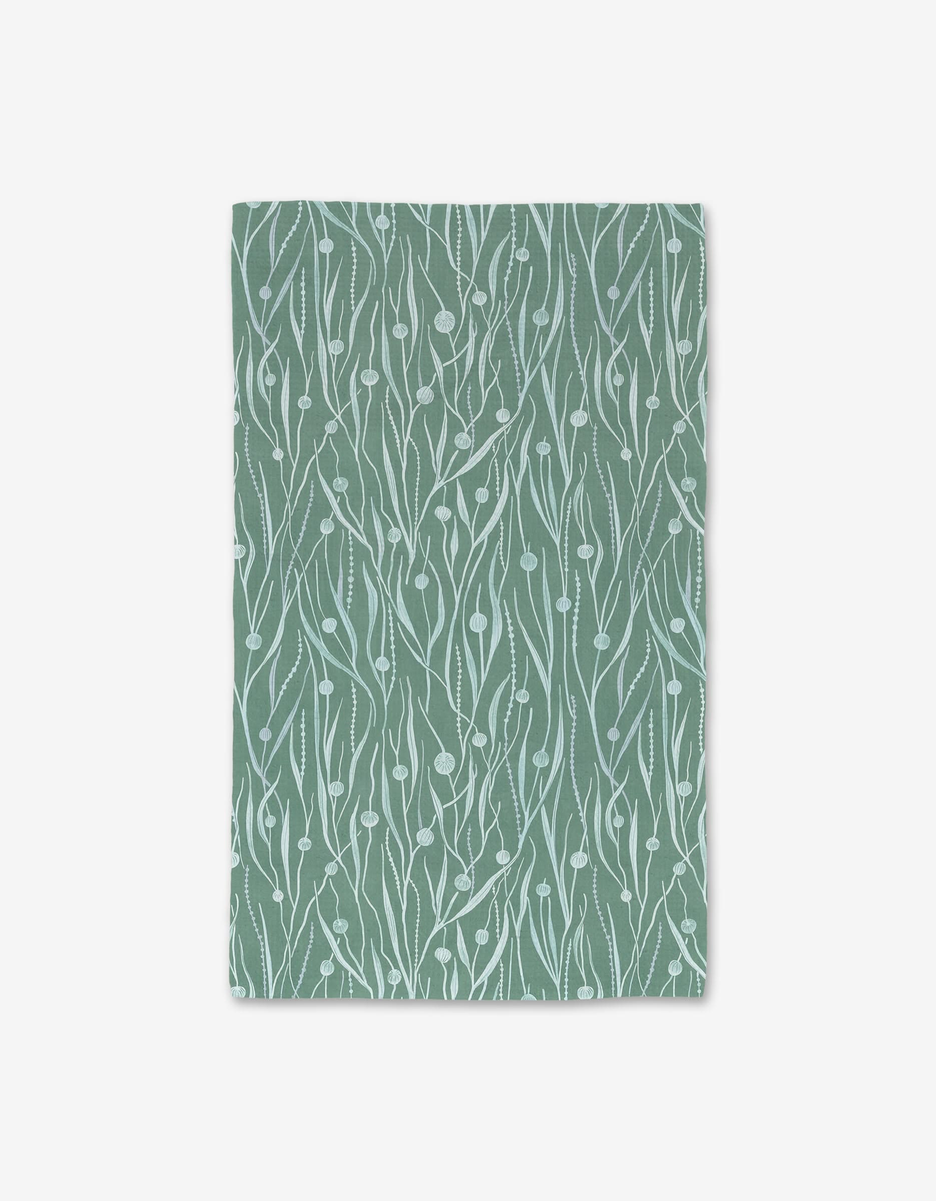 Kelp by Katie OShea is a green rectangular mat made from recycled materials, featuring a white abstract botanical pattern with wavy lines and small leaf shapes, shown on a plain white background.