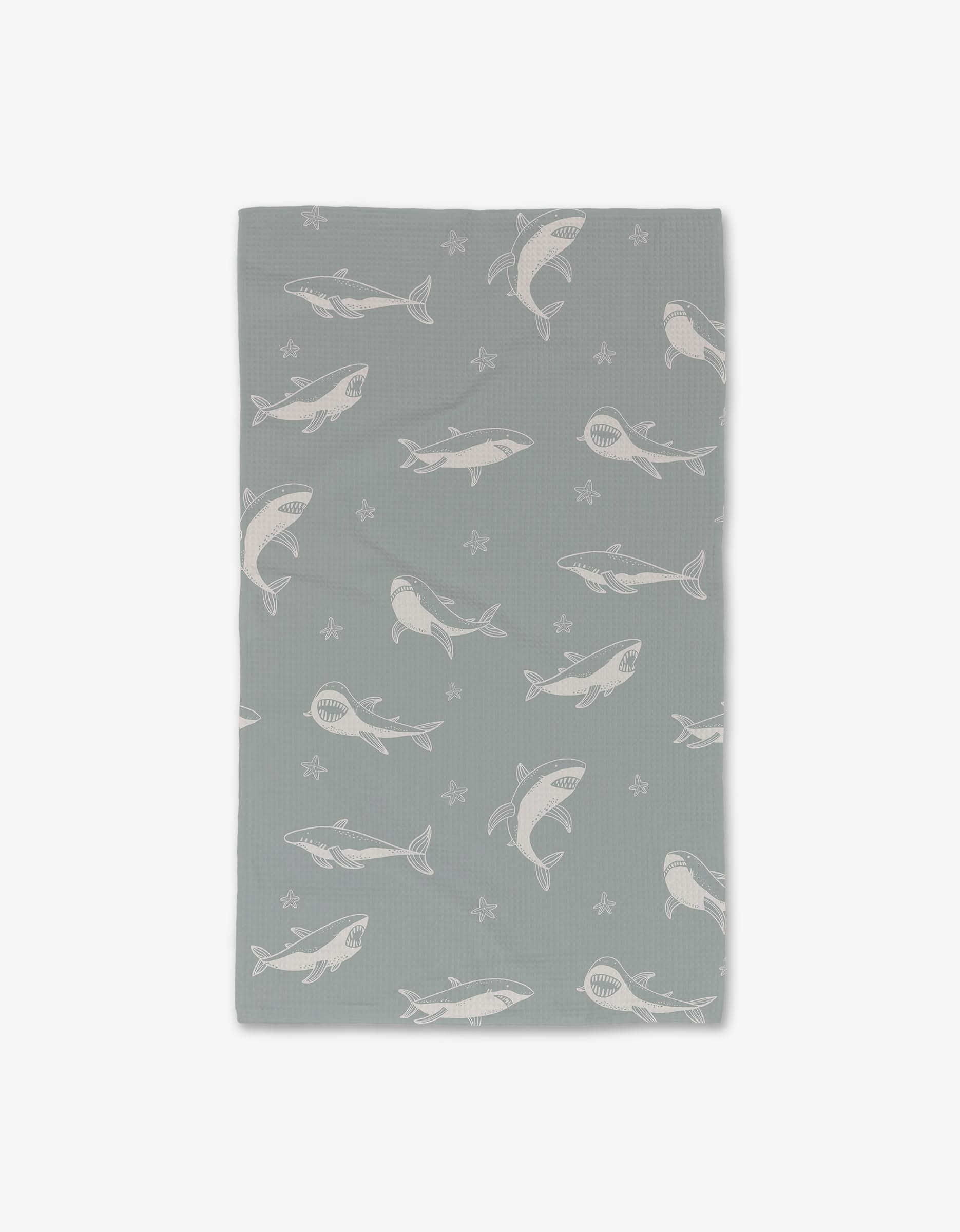 The Toothy Tales blanket by Janna Sue Design is a gray rectangle with white sharks and starfish, made from ultra-absorbent material for a cozy blend of style and function.