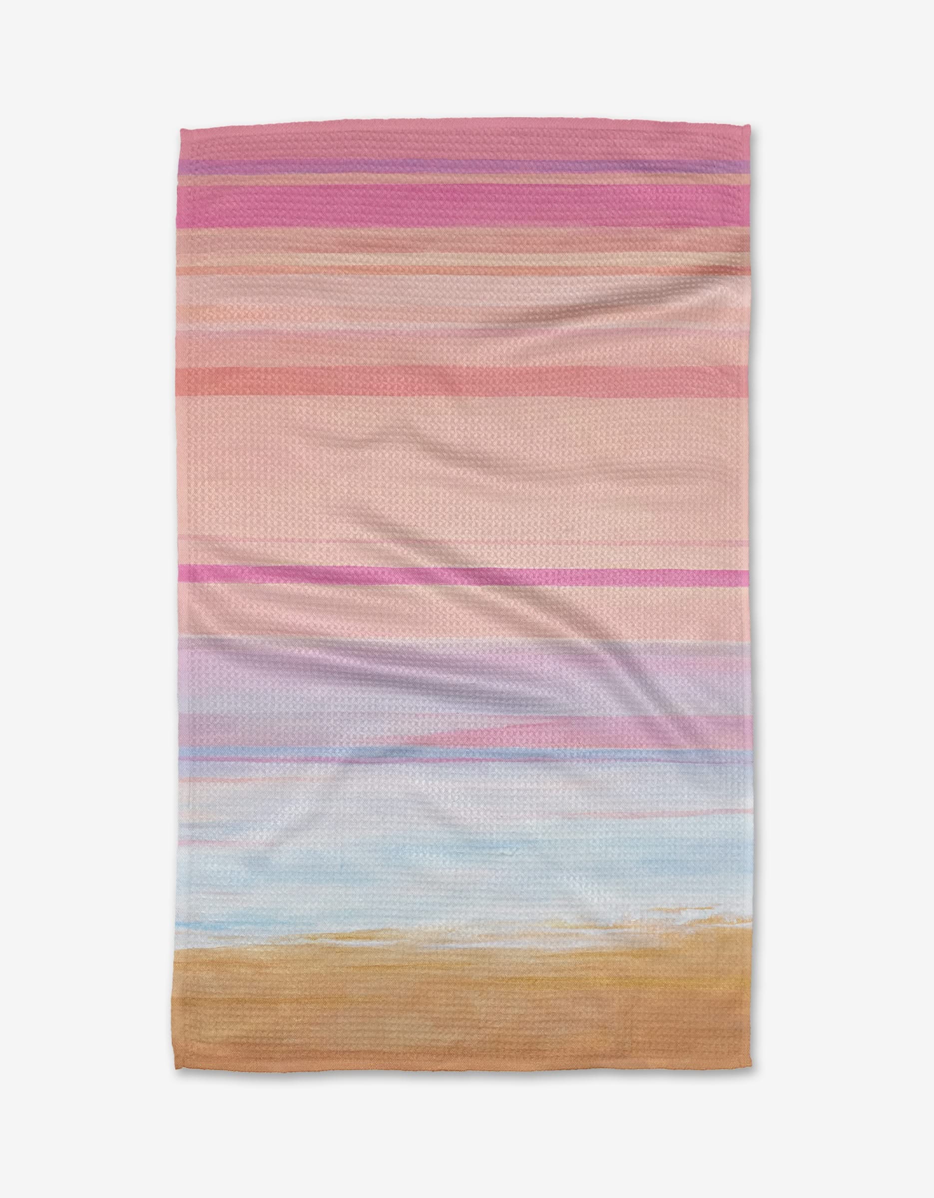 The Blush tea towel by Stefanie Bales features horizontal stripes in pink, purple, blue, and tan on Geoweave fabric, evoking a pastel beach scene. Shown laid flat on a white background.