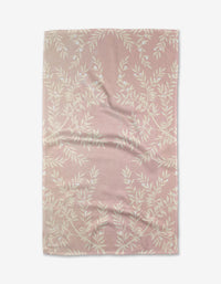 The Charlotte tea towel by Becki Owens features pink textured Geoweave™ fabric with a white leafy branch pattern, shown laid flat with visible creases and folds on a white background.