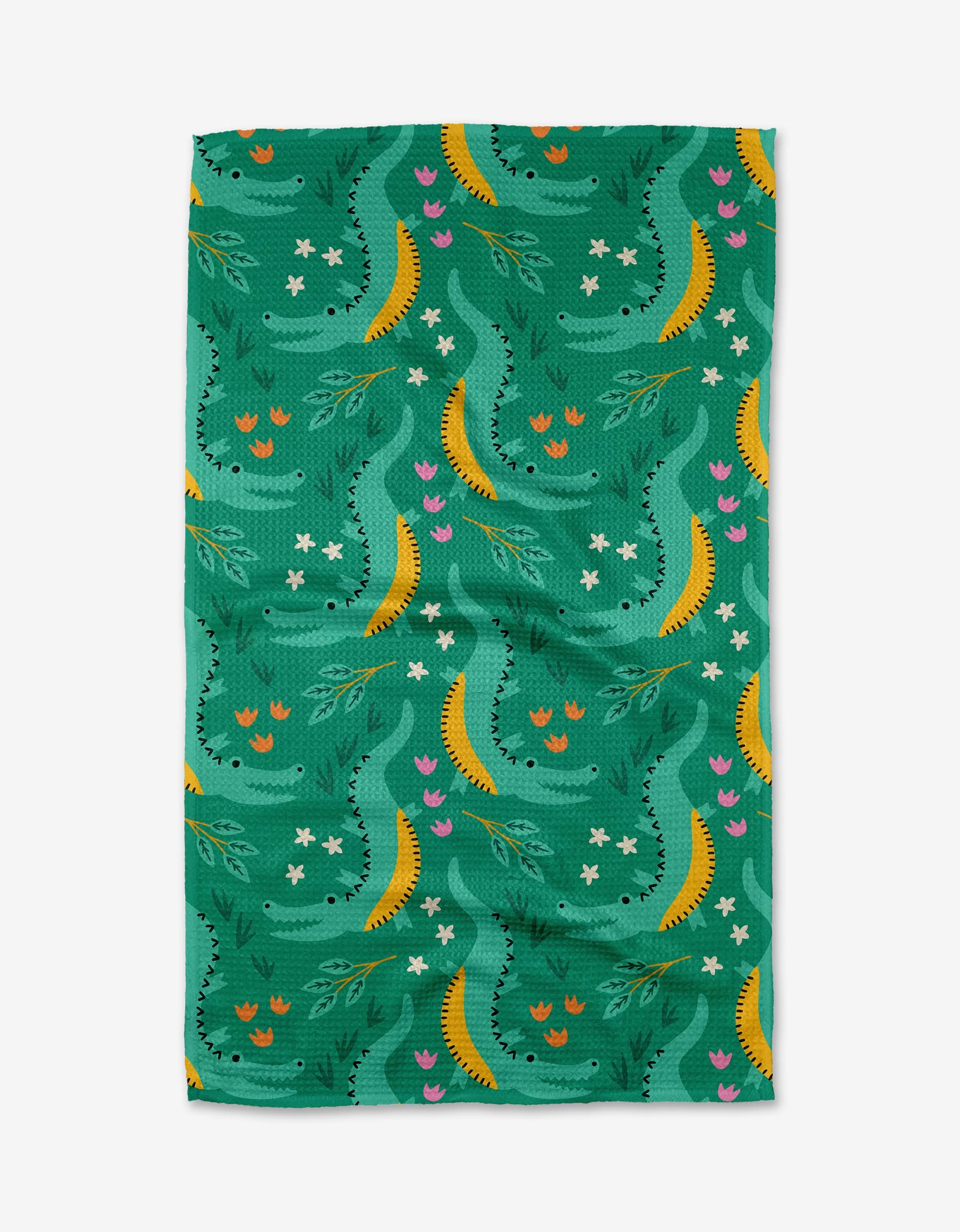 The Crocodiles tea towel by Genna Blackburn features a green rectangular design with yellow crescents, white star-like dots, pink and red tulip-style flowers, and abstract leaves on soft recycled Geoweave™ fabric.