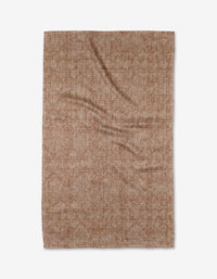 A flat, rectangular Debra Rust tea towel by Becki Owens in brown, featuring a subtle textured pattern and crafted from ultra-absorbent Geoweave fabric. Shown against a white background with a few gentle creases on the material.