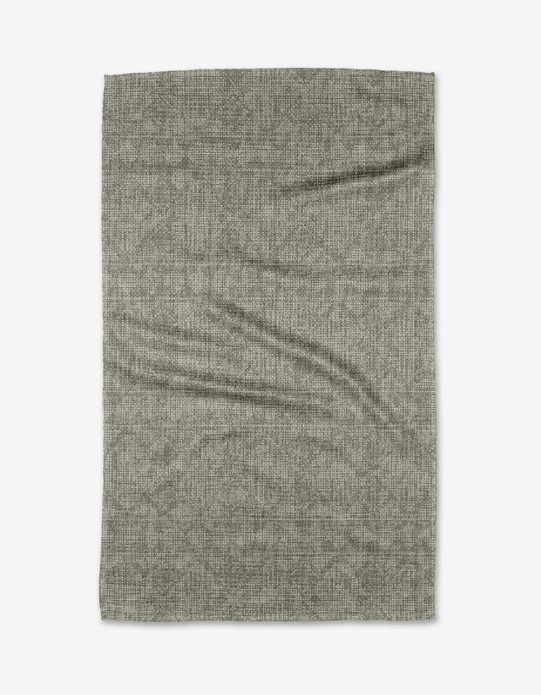 The Debra Sage tea towel by Becki Owens is a rectangular, textured gray piece made from recycled materials, shown laid flat on a white background with visible creases and folds.