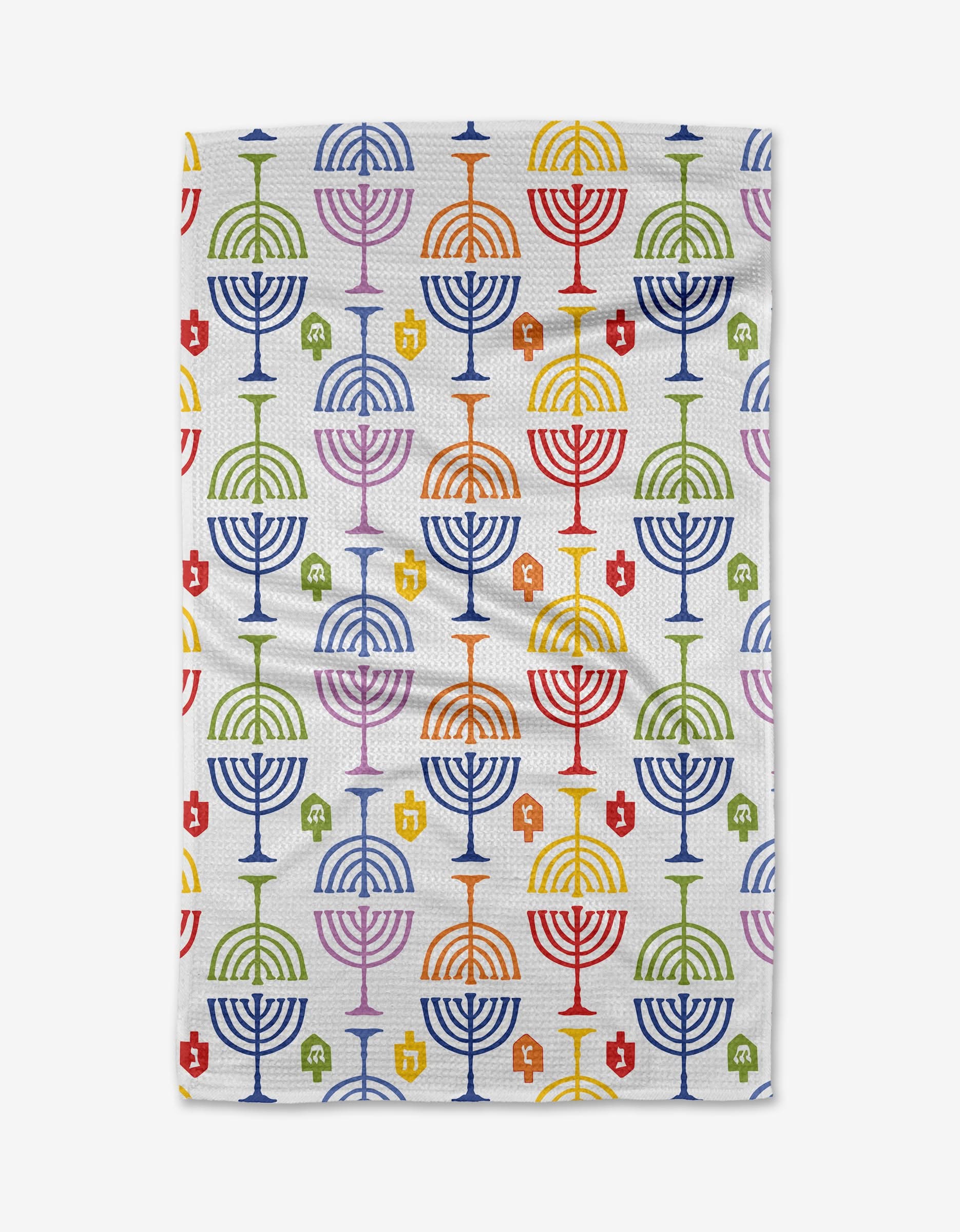 The Mindfulnice Festival of Lights kitchen towel is made from recycled materials and features a white background with a repeating pattern of colorful menorahs and dreidels in blue, red, green, orange, and yellow.