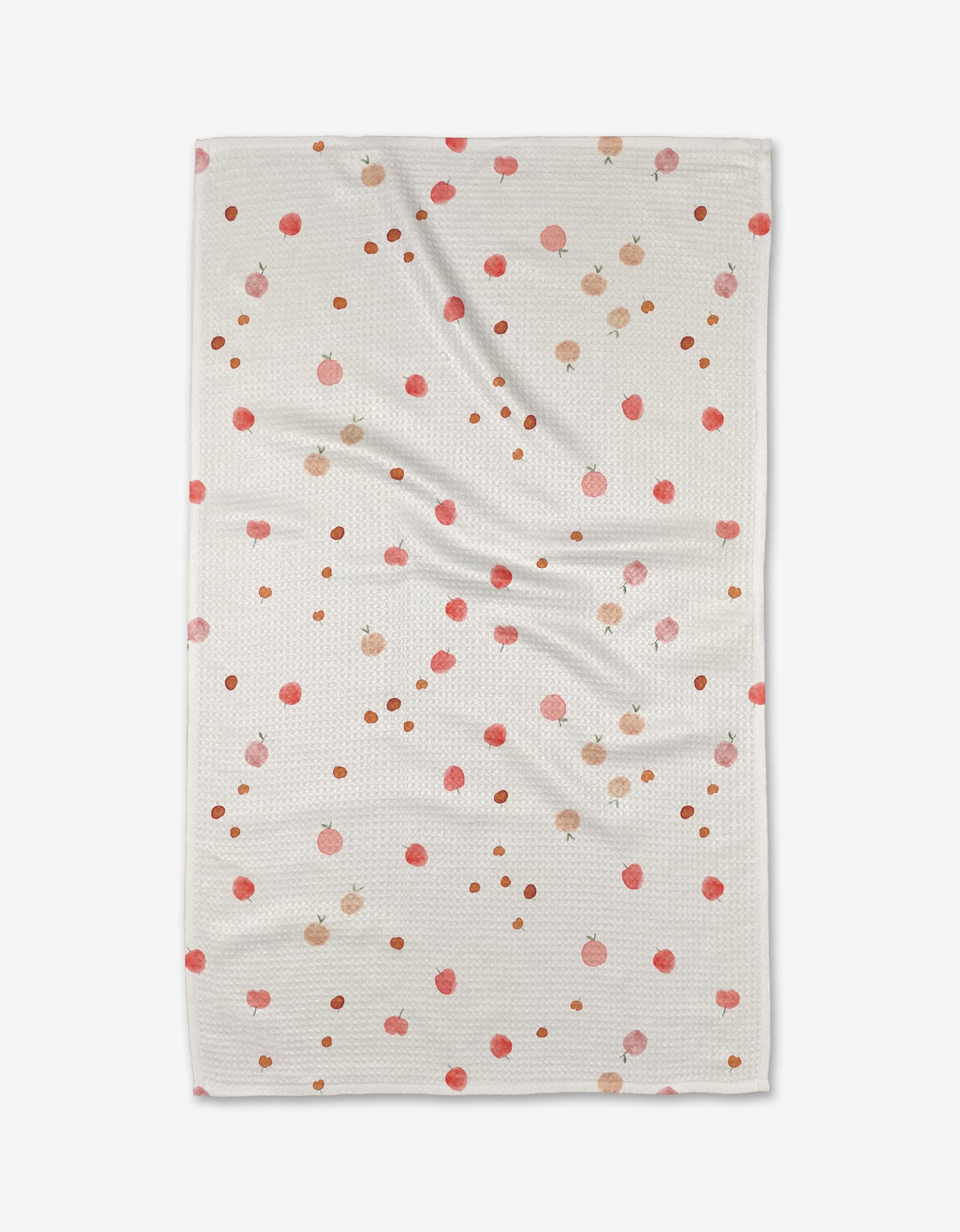 The Fruity blanket by Anee Shah is a white, textured throw with small pink and orange pomegranate illustrations and brown dots, resembling an ultra-absorbent towel. It’s shown laid flat with gentle wrinkles.