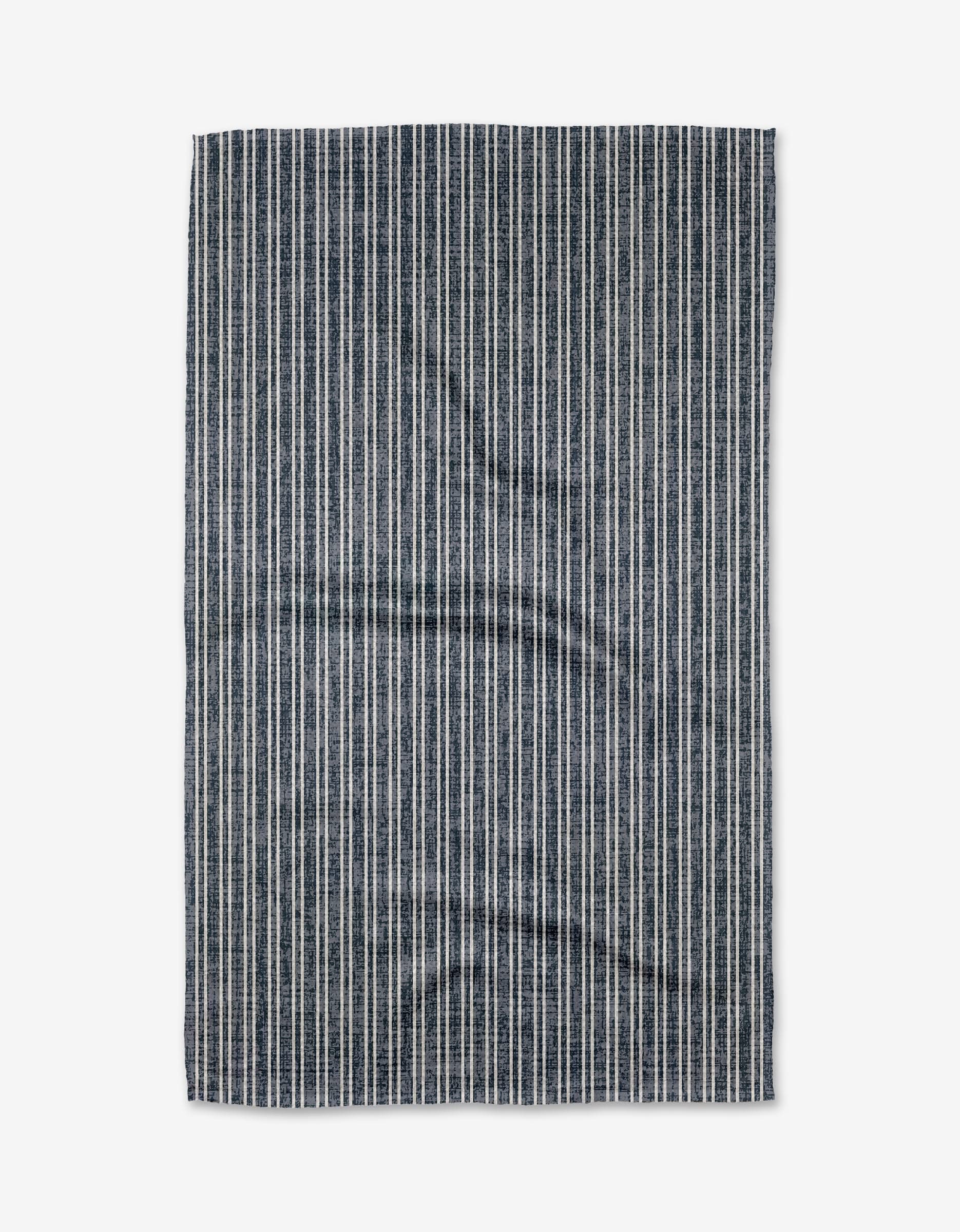 The Garff Blue Tea Towel by Becki Owens features vertical navy blue and white stripes, laid flat on a white background, and is made from durable Geoweave fabric.
