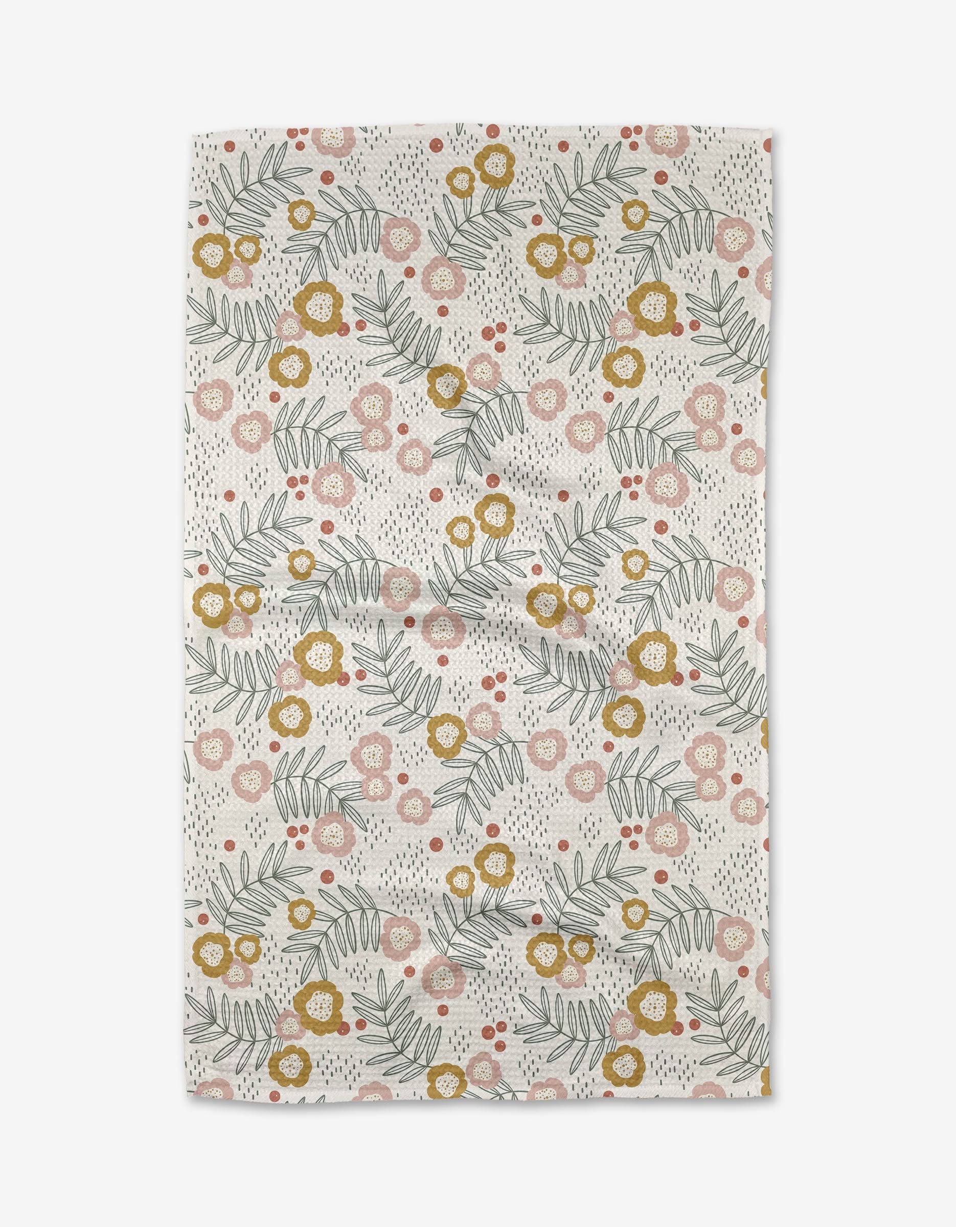The Savannah Multi Tea Towel by Charlie Rowan Designs is made from Geoweave fabric and features pink, yellow, and orange flowers with green fern-like leaves and black dots on a white background.
