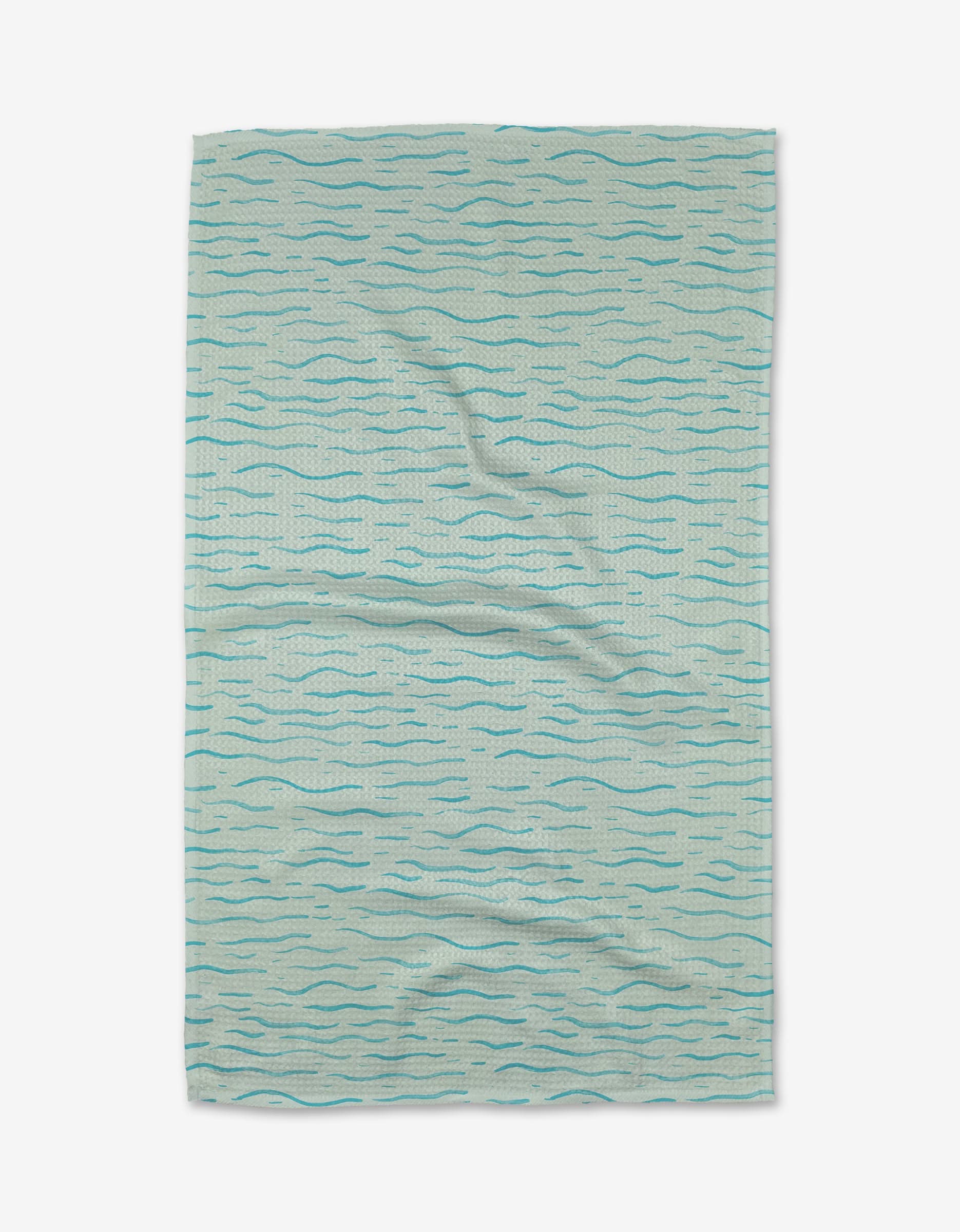 The Just Keep Swimming tea towel by Katie OShea is light blue, rectangular, and made from Geoweave™ fabric. It features a wavy, water-inspired pattern in dark blue tones and is shown slightly wrinkled on a white background.