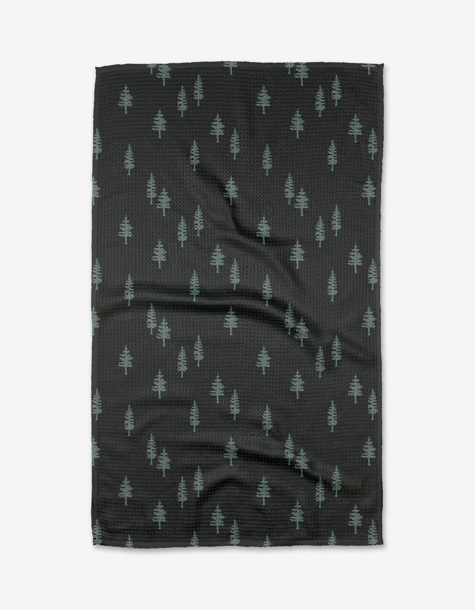 The Lake Pine tea towel by Coit Creative is made of black Geoweave fabric with a pattern of small, light green pine trees evenly distributed across the surface.