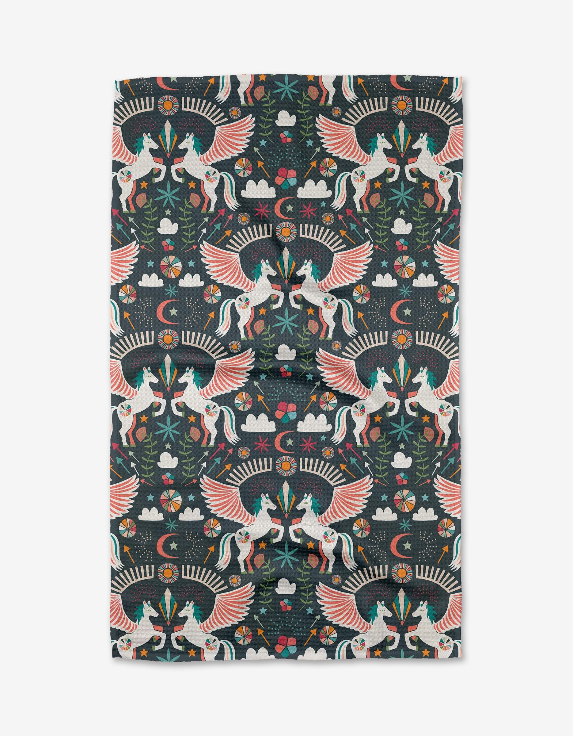 Jessica Swift’s Magical Moments kitchen towel showcases colorful winged unicorns, flowers, stars, clouds, and foliage in a symmetrical folk-art style on a dark background.