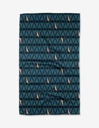 The Northbound Geoweave™ tea towel by Twig + Spark features dark blue triangles forming diamond patterns with small beige accents, all set on a white background.