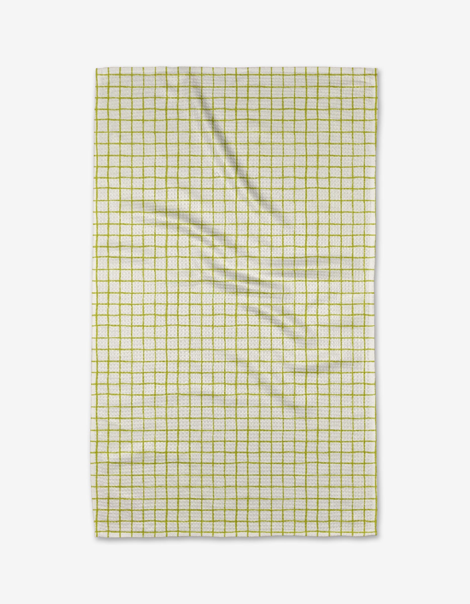 The On the Lawn tea towel by Kayla Ann is a rectangular, white kitchen towel featuring a grid of thin yellow lines. Absorbent and lightly creased, it’s shown flat against a white background.